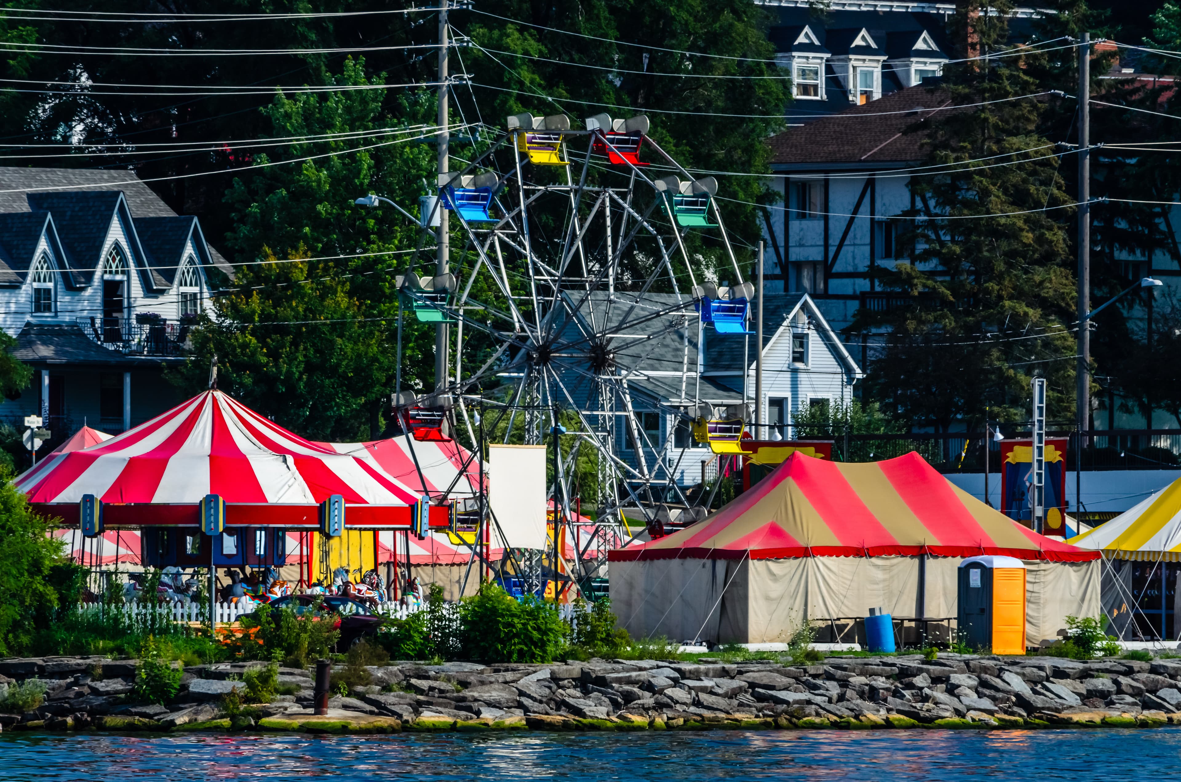 Colorful tents and ferris wheel of a small waterfront carnival Colorful tents of a small waterfront carnival