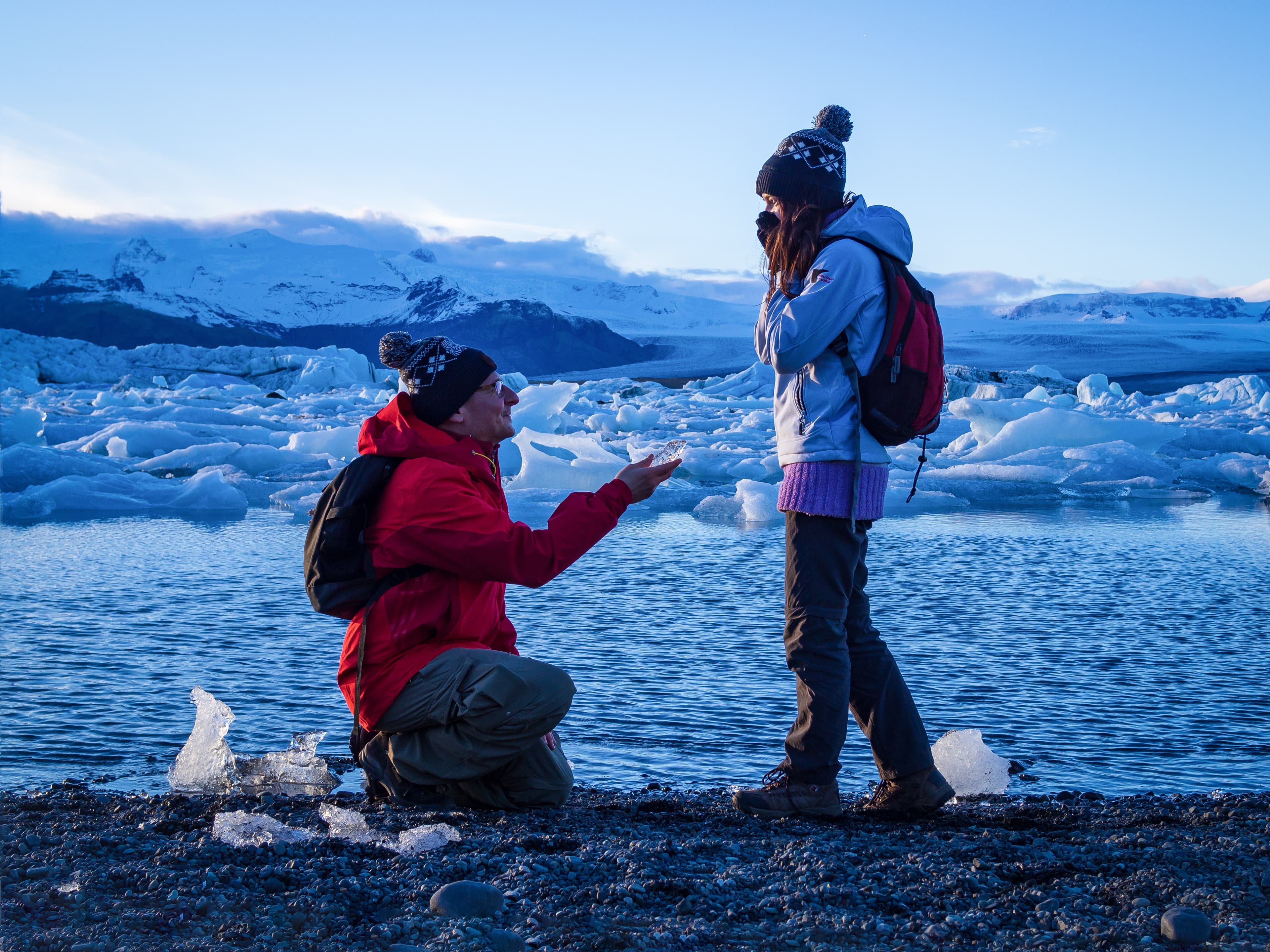 Man is making the marriage proposal to a girl with the peace of ice in among icebergs Man is making the marriage proposal to a girl with the peace of ice in among icebergs