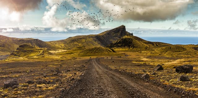 Scenic road and surreal landscape at the Highlands of the Snaefellsnes peninsula near the glacier Snaefellsjokull in Iceland. The wooly gray green moss thrives vibrant above the young lava fields. Scenic road and surreal landscape at the Highlands of the Snaefellsnes peninsula