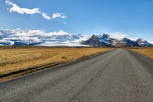 Gravel road in Iceland with mountains and glacier in the background Fjallsarlon-glacier-lagoon-zodiac-boat 8