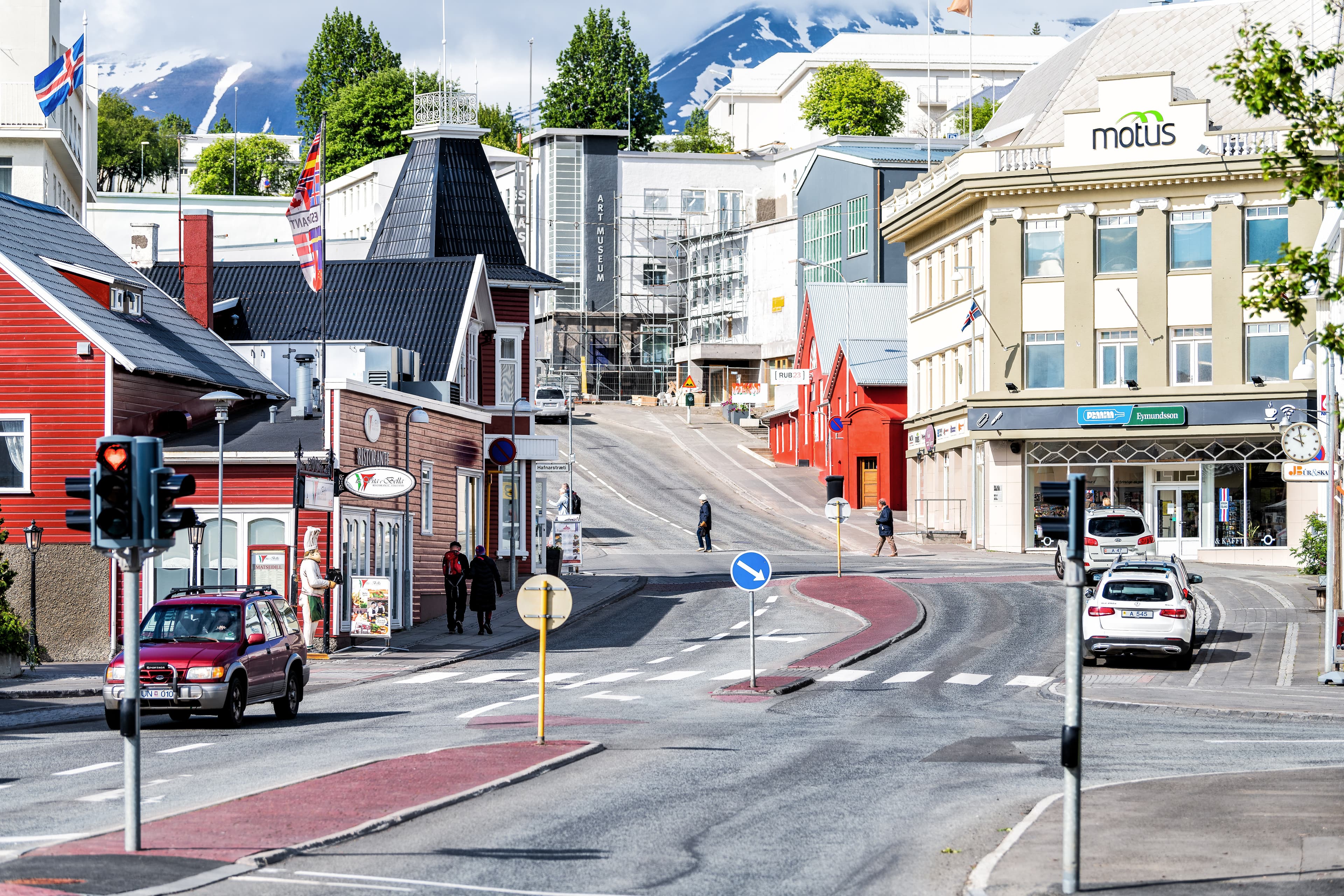Akureyri, Iceland - June 17, 2018: Cityscape, skyline view of small town, city, street, road, people walking on sidewalk, houses, buildings, restaurants, snow covered mountains in summer Akureyri, Iceland - June 17, 2018: Cityscape, skyline view of small town, city, street, road, people walking on sidewalk, houses, buildings, restaurants, snow covered mountains in summer