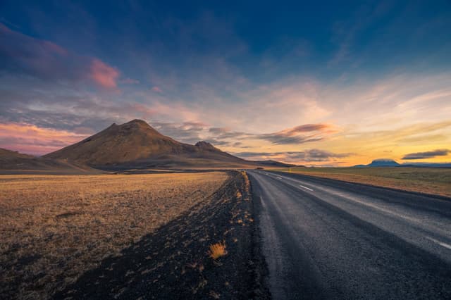 Iceland. Colorful landscape at sunset with dark road Iceland. Colorful landscape at sunset with dark road