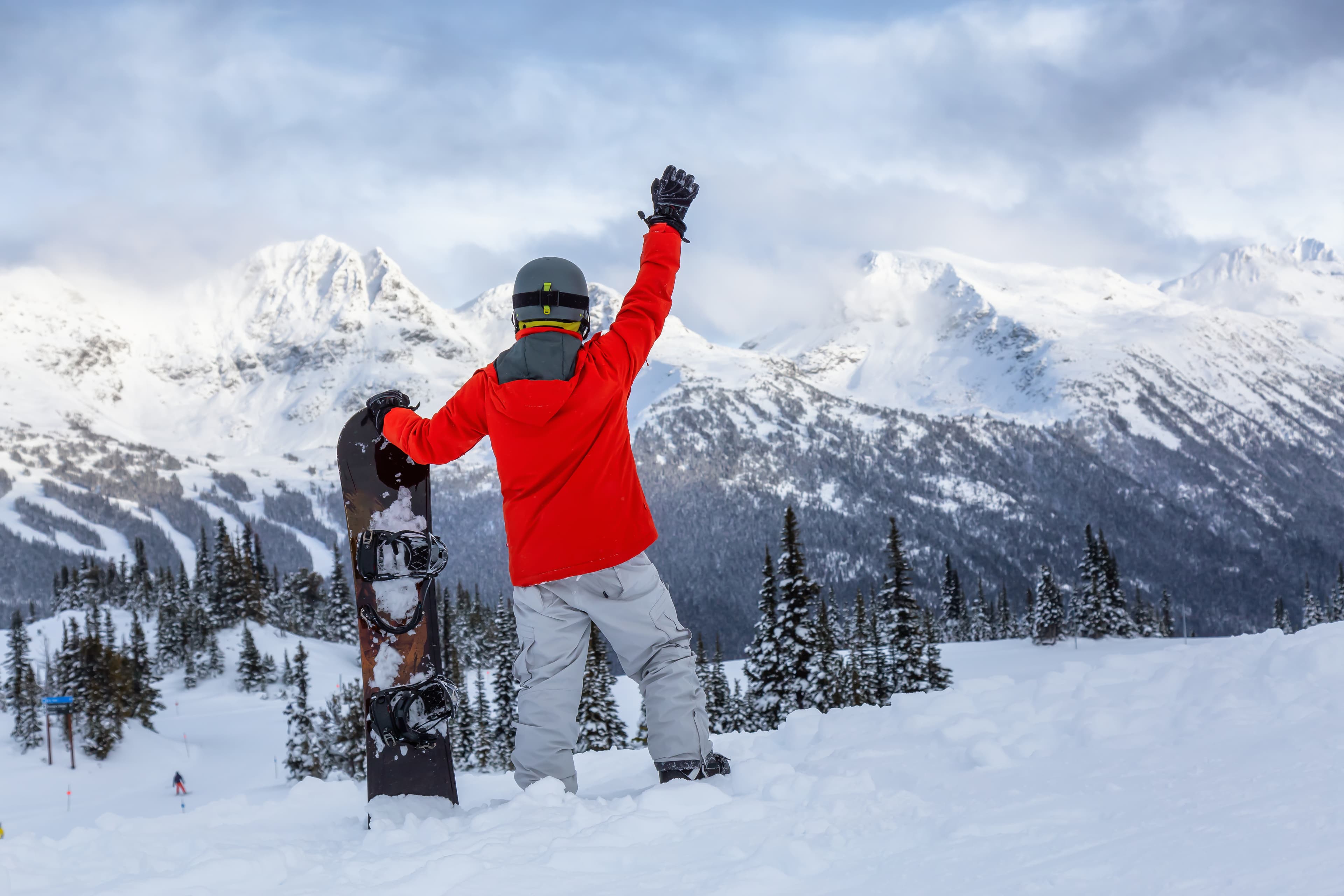 Male Snowboarder is riding down a ski run in wintertime. Taken on Whistler Mountain, British Columbia, Canada. Male Snowboarder is riding down a ski run in wintertime