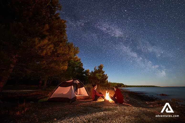 couple-with-a-tent-near-the-campfire-stargazing-at-the-lake-superior-in-canada