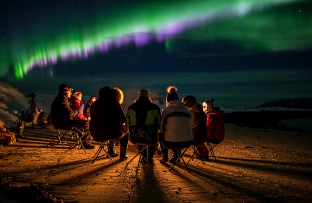 People-sitting-by-the-fire-and-aurora-borealis