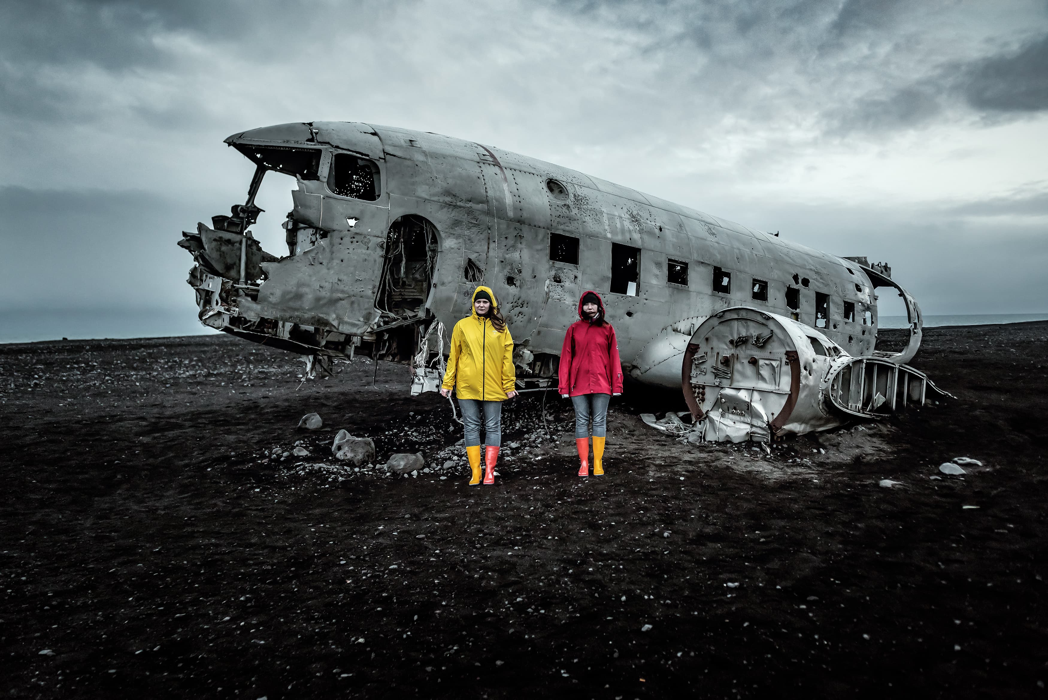 Two girl in yellow and red clothes and Solheimasandur Plane Wreck in Iceland Two girl in yellow and red clothes and Solheimasandur Plane Wreck