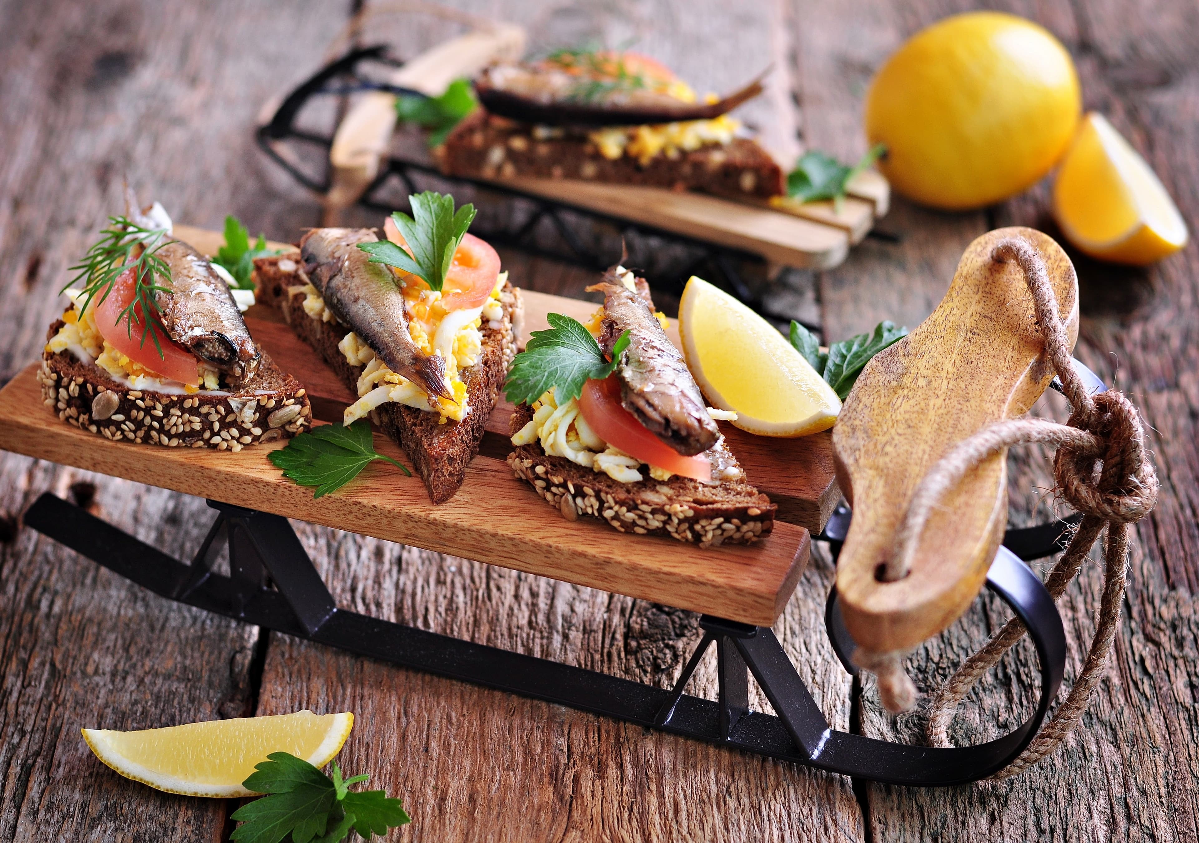 French toast with sprats, tomato, egg and garlic on a small wooden sled.