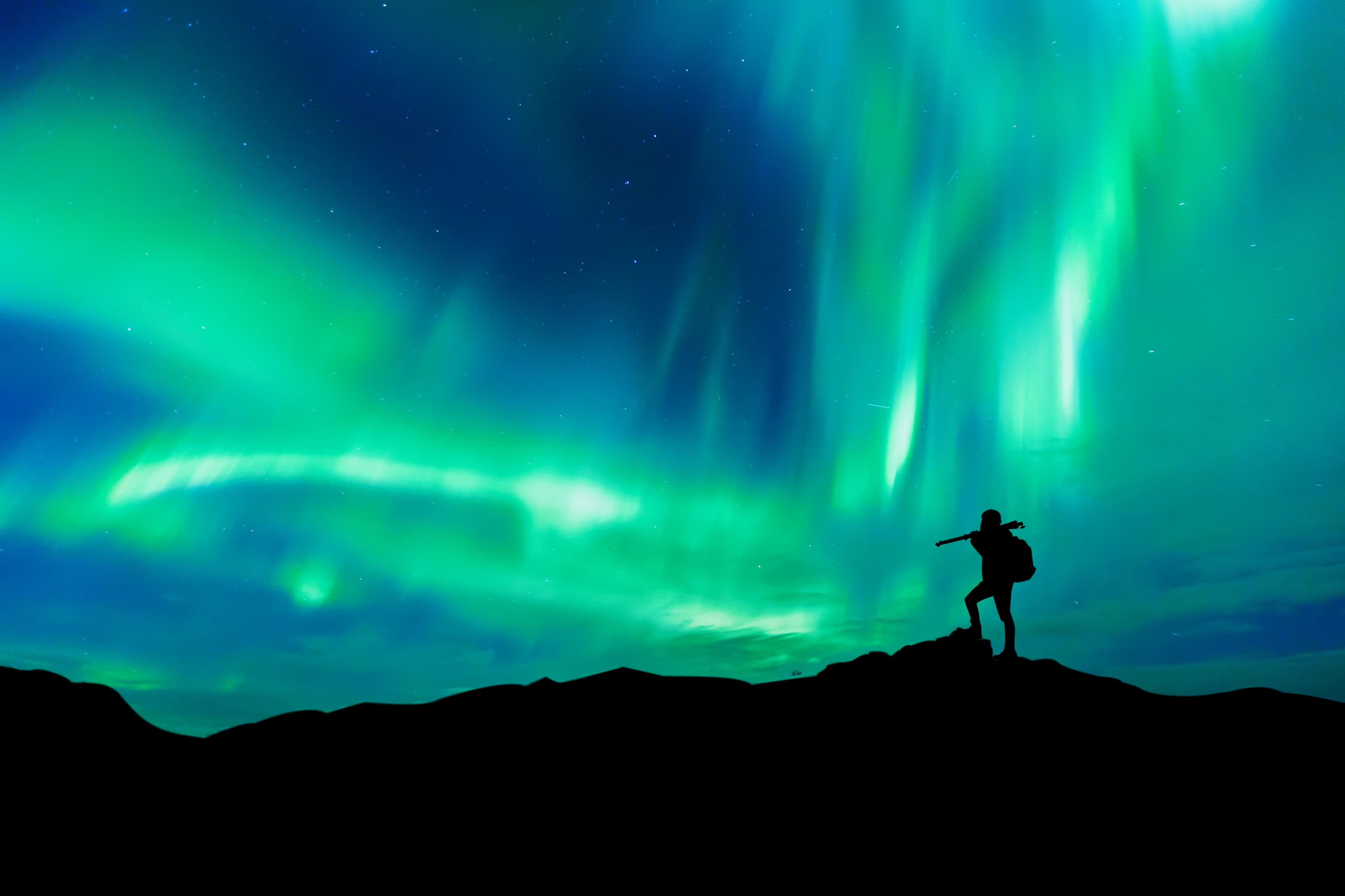 Aurora borealis with silhouette standing photographer on the mountain.Freedom traveller journey concept Aurora borealis with silhouette standing photographer on the mountain.Freedom traveller journey concept
