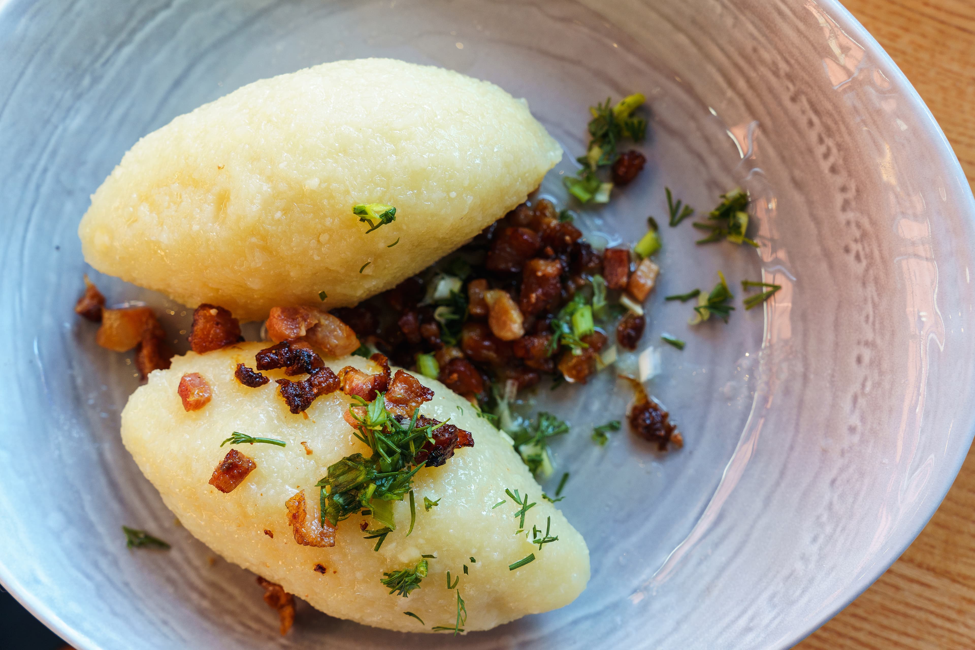 Lithuanian national dish zeppelins with fried bacon and herbs, top view Lithuanian national dish zeppelins or Cepelinai or didzkukuliai with fried bacon and herbs, top view.