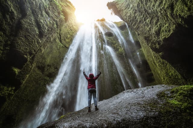 Traveler stunned by Gljufrabui waterfall cascade in Iceland. Located at scenic Seljalandsfoss waterfall South of Iceland, Europe. It is top beautiful destination of popular tourist travel attraction. Traveler stunned by Gljufrabui waterfall cascade in Iceland. Located at scenic Seljalandsfoss waterfall South of Iceland, Europe. It is top beautiful destination of popular tourist travel attraction.