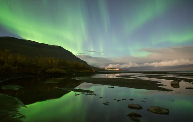 Northern lights dancing over calm lake in Abisko national park