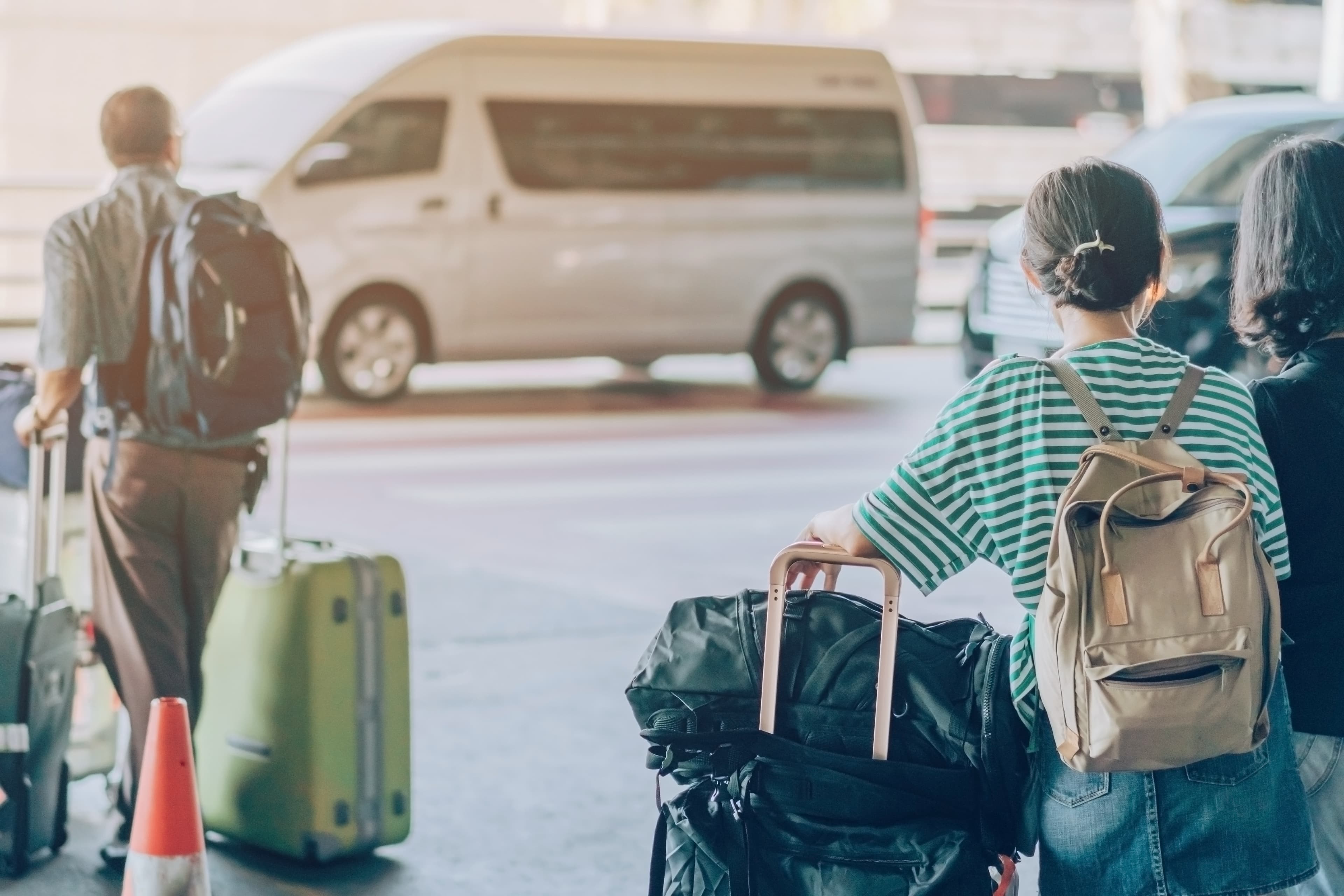 Passengers with big roller luggage stand to wait for the car to pick up at airport arrival terminal. Passengers with big roller luggage stand to wait for the car to pick up at airport arrival terminal.