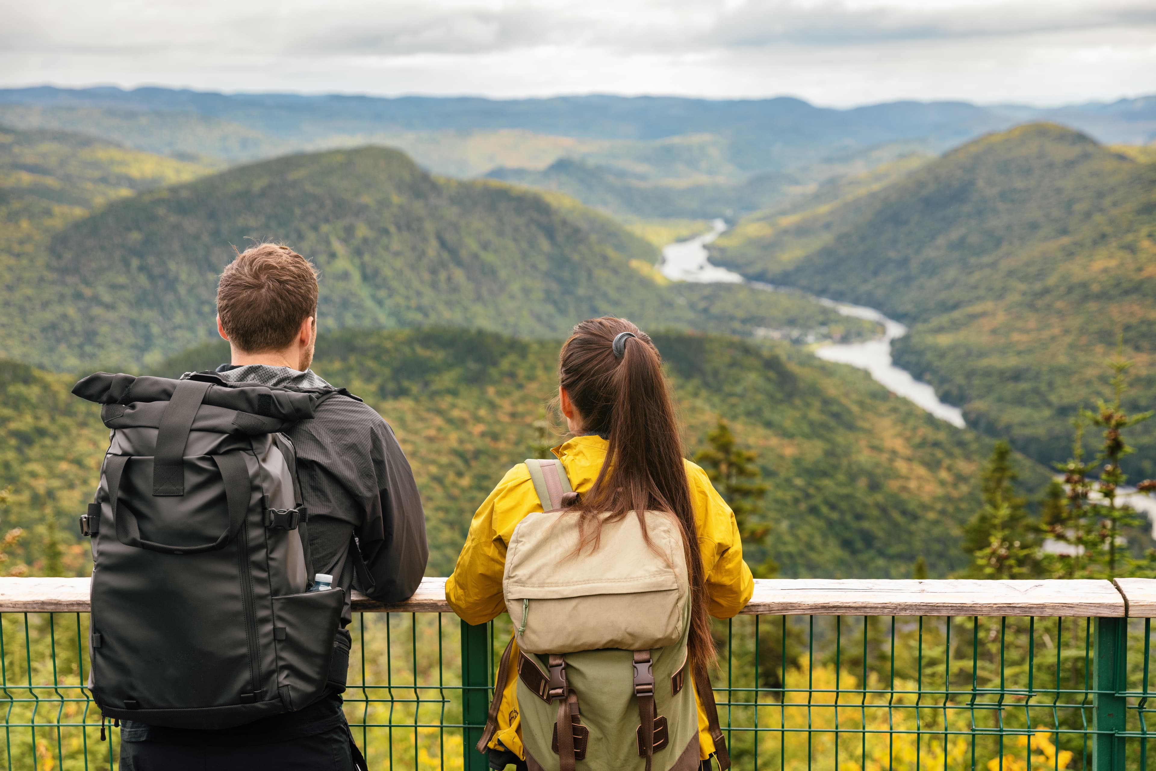 Hike couple camping with backpacks in Quebec National Park in Autumn season, Canada forest travel lifestyle. Tourists looking at view of Jacques Cartier National Park. Hike couple camping with backpacks in Quebec National Park in Autumn season, Canada forest travel lifestyle. Tourists looking at view of Jacques Cartier National Park.