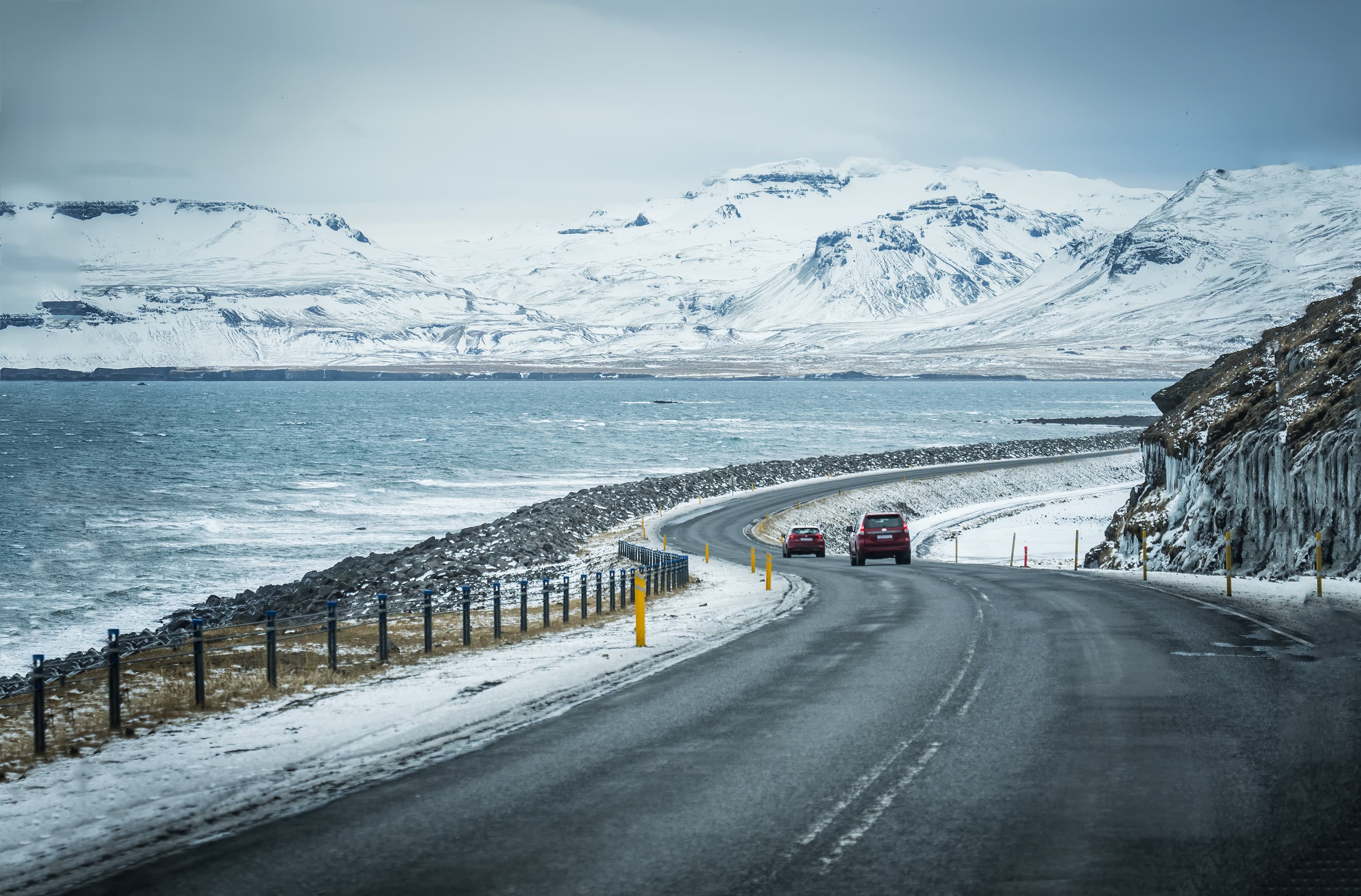 Modern car riding on asphalt countryside road towards magnificent snowy mountains during trip through Iceland Car riding towards mountains in Iceland in winter