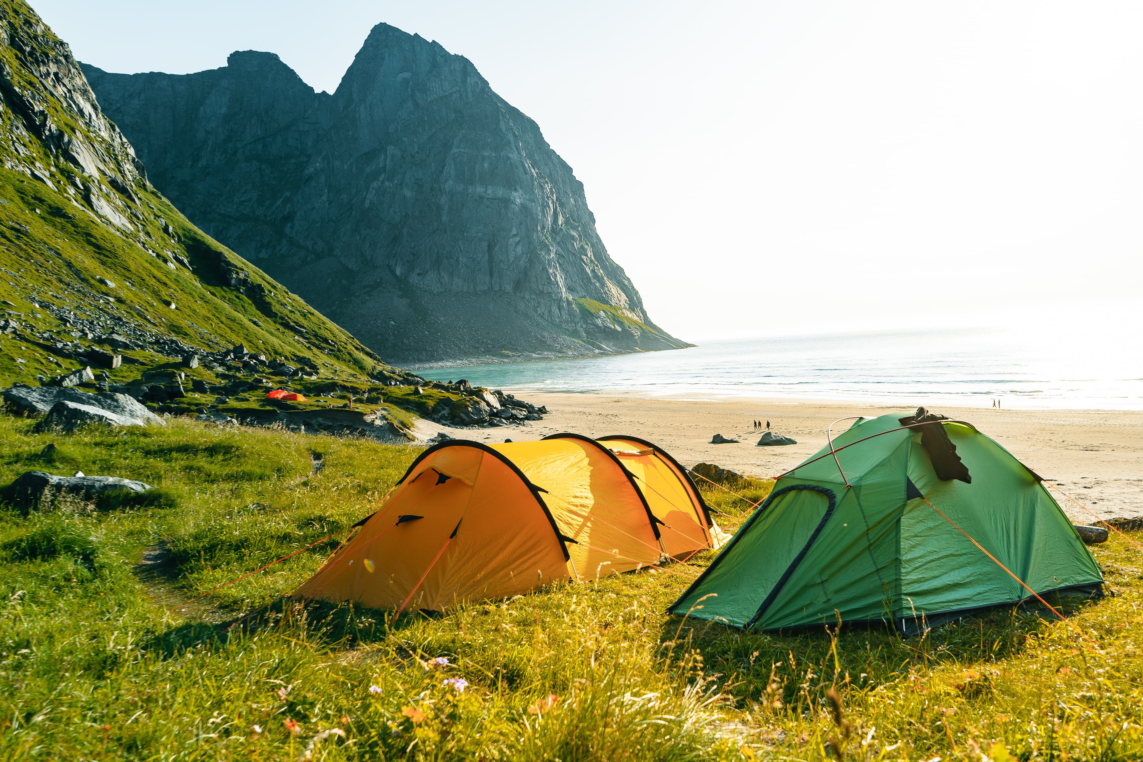 Tent on a sandy beach. Ocean Coast during a vibrant summer sunset. Taken in Kvalvika beach, Lofoten Island, Norway