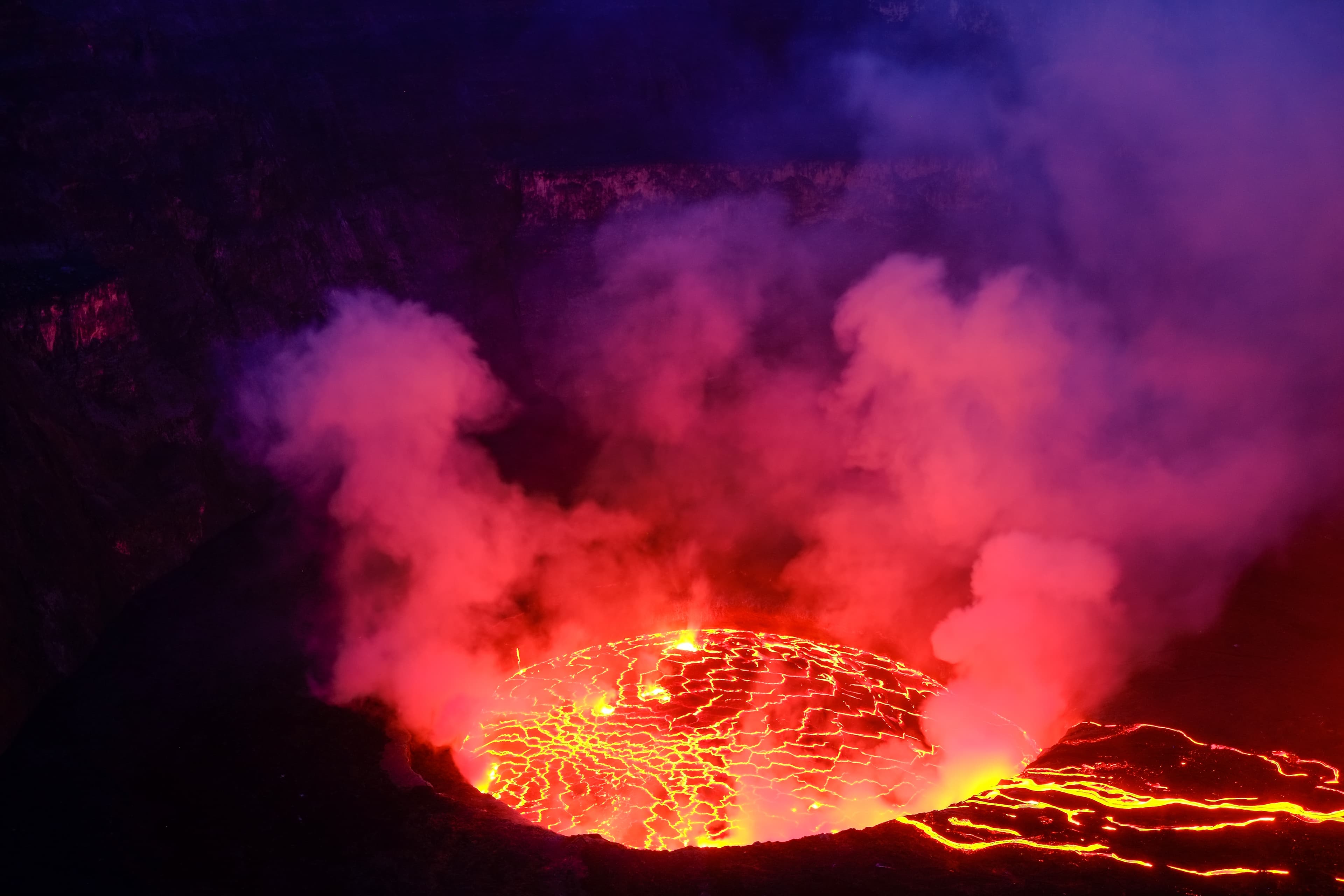 Lava and steam in crater of Nyiragongo volcano in Virunga National Park in Democratic Republic of Congo, Africa. Picture taken during dusk with blue coloured smoke rising up. Lava and steam in crater of Nyiragongo volcano in Virunga National Park in Democratic Republic of Congo, Africa