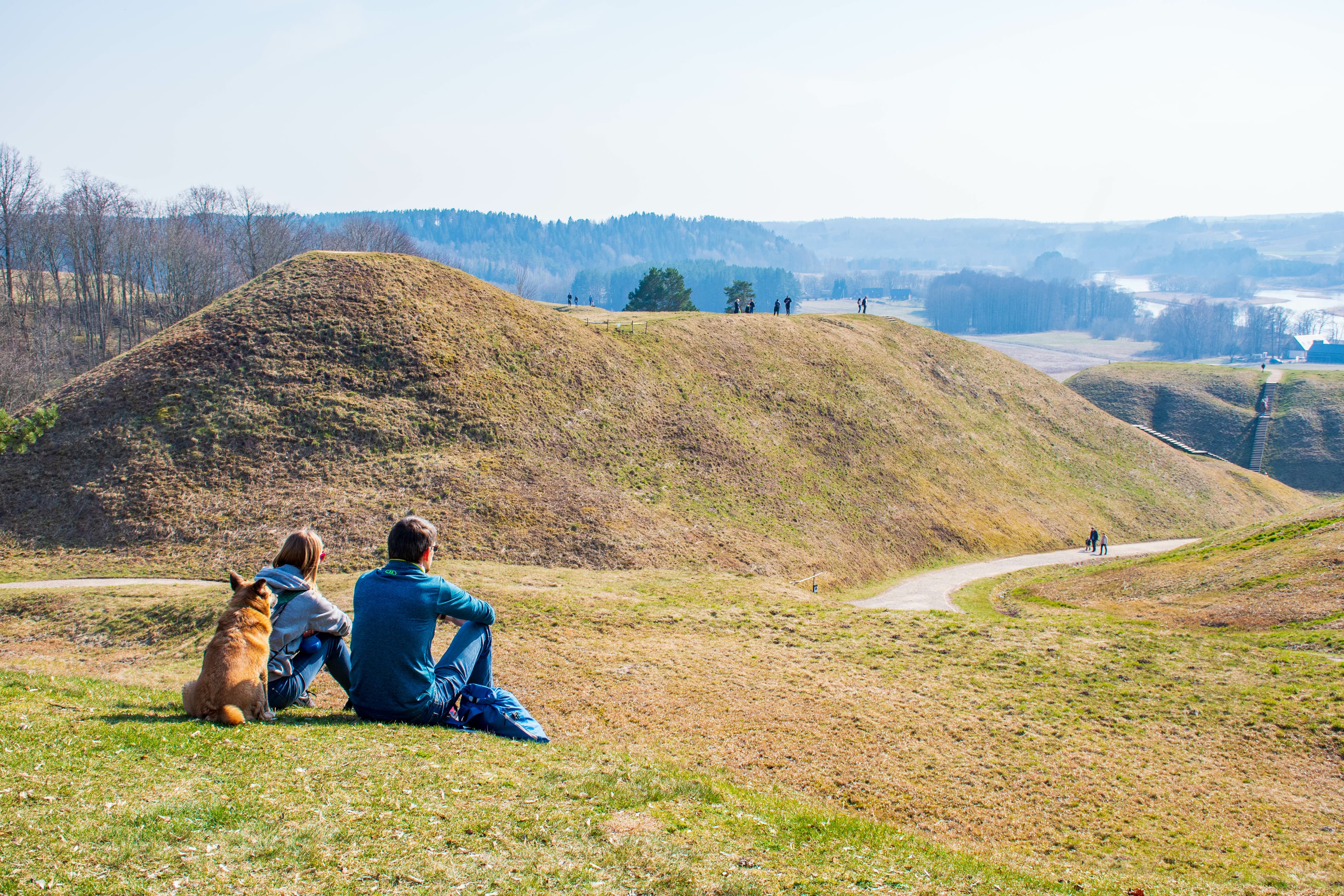 Hills of Kernave, Lithuania, UNESCO world heritage, was a medieval capital of the Grand Duchy of Lithuania, tourist attraction and an archaeological site. Panorama of valley with couple and dog