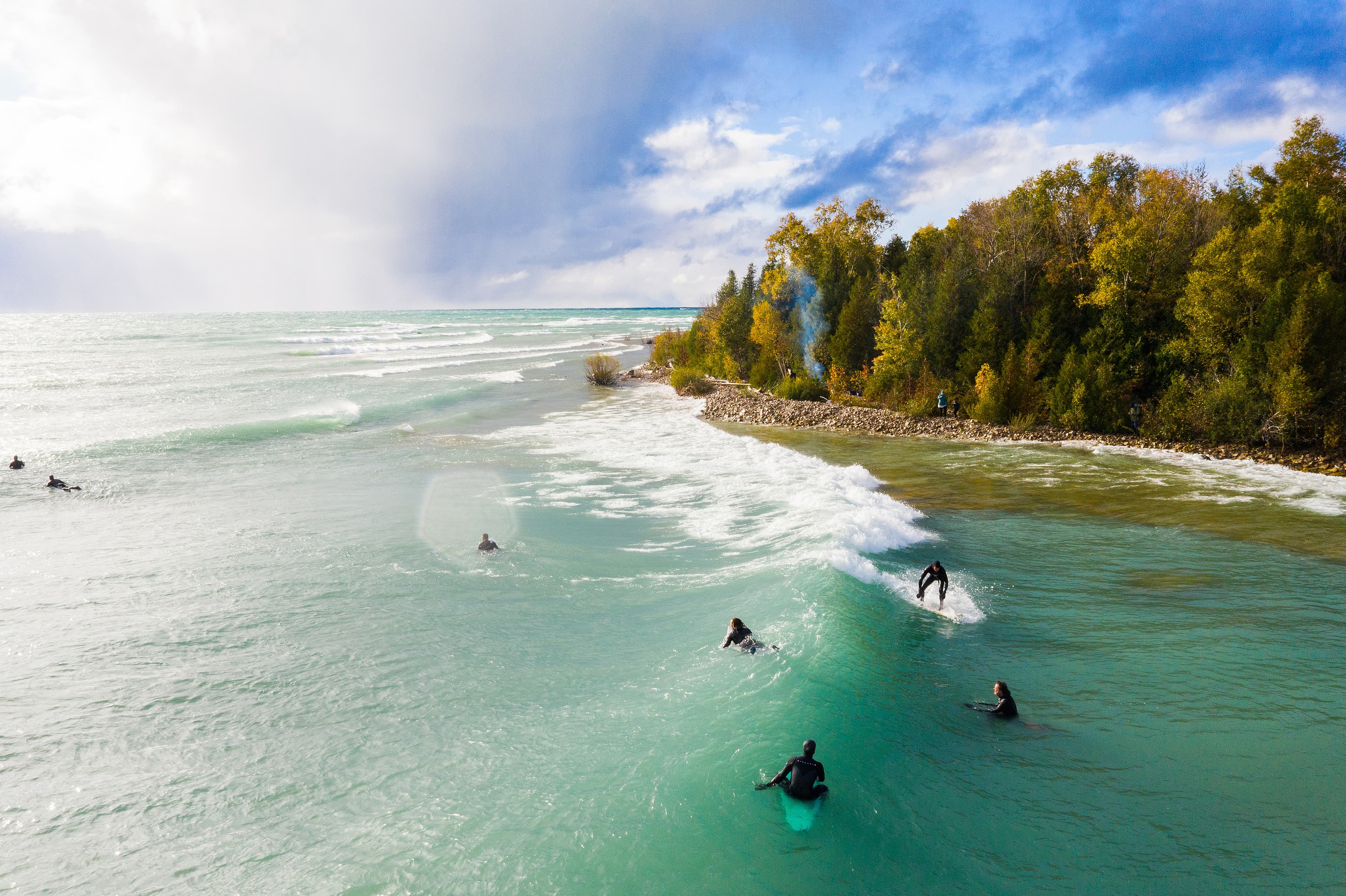 Lake Huron, Ontario, Canada - October 17, 2018: Aerial view of a group of Great Lakes surfers catching waves during an autumn storm. Lake Huron, Ontario, Canada - October 17, 2018: Aerial view of a group of Great Lakes surfers catching waves during an autumn storm.