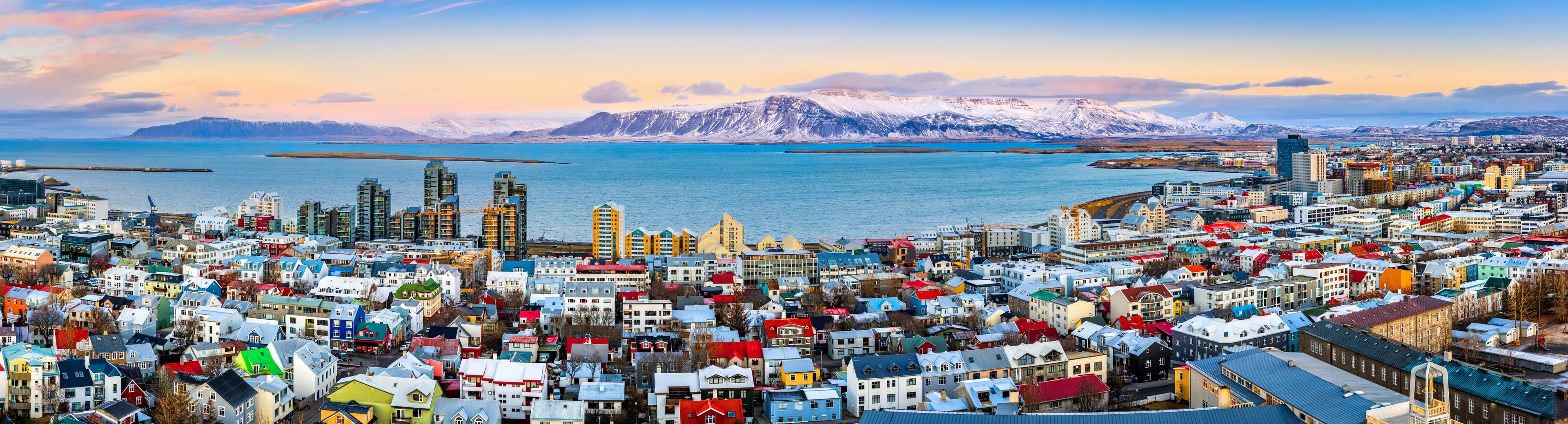 Aerial panorama of downtown Reykjavik at sunset with colorful houses and snowy mountains in the background Aerial panorama of downtown Reykjavik at sunset with colorful houses and snowy mountains in the background