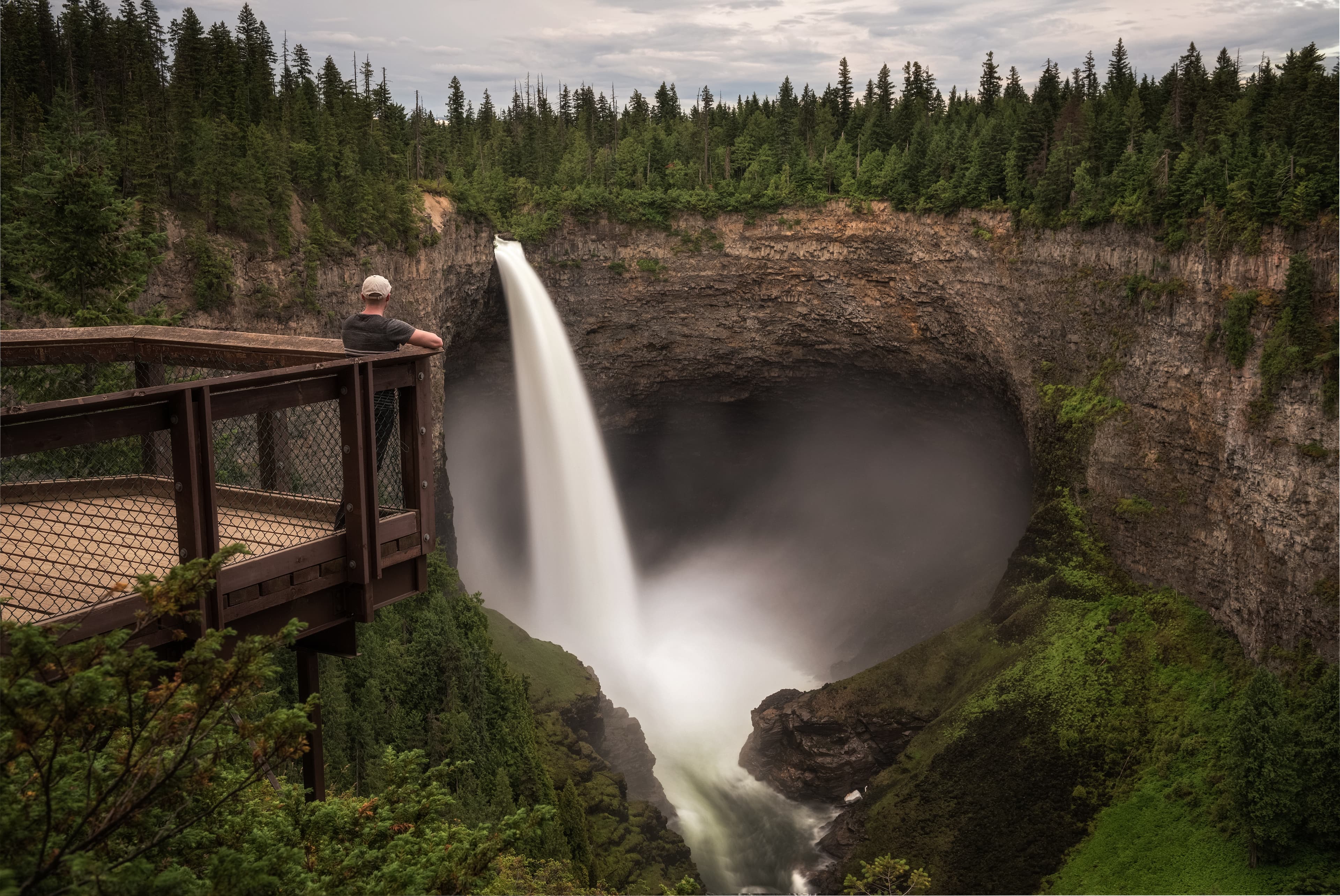 Tourist standing on an outlook platform and looking at the Helmcken Falls in Wells Gray Provincial Park near Clearwater, Canada. Long exposure. Tourist at Helmcken Falls in Wells Gray Provincial Park in Canada