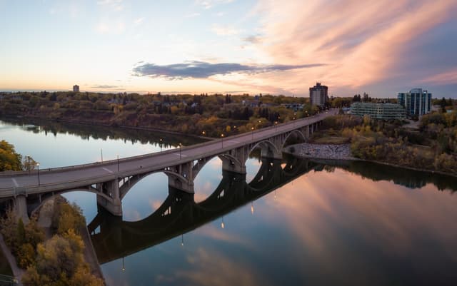 Aerial panoramic view of a bridge going over Saskatchewan River during a vibrant sunrise in the Fall Season. Taken in Saskatoon, SK, Canada. Saskatoon City Attraction 3