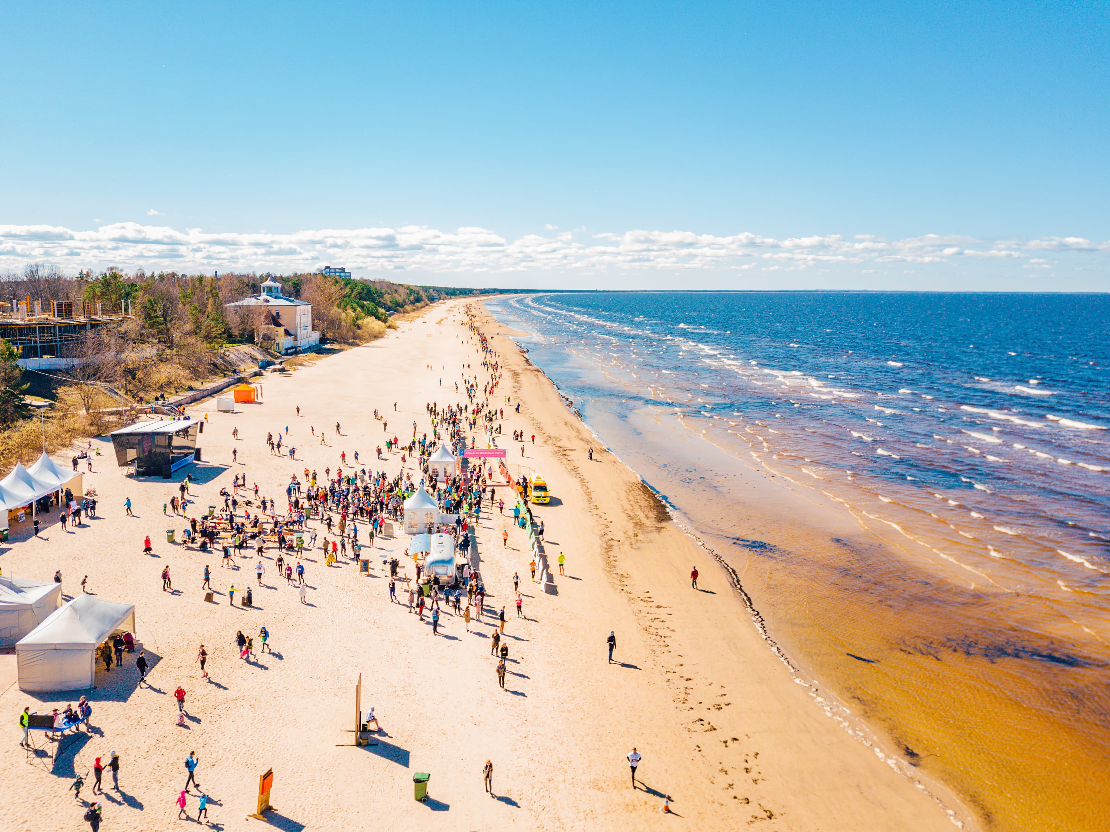 Aerial view from drone on crowd of people who is starting are running on marathon event by the sea shore in Jurmala, Latvia.