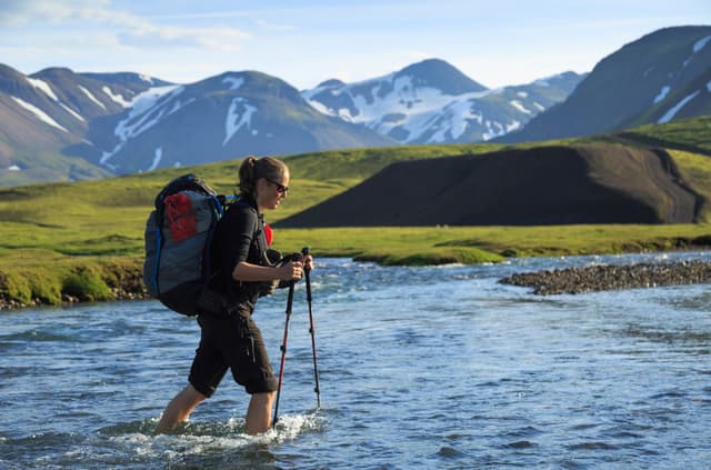 Female hiker crossing a river on the Laugavegur trail on Iceland. Female hiker crossing a river on the Laugavegur trail on Iceland.