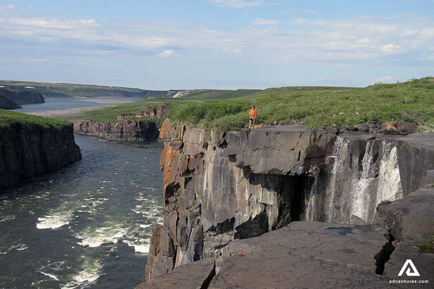 man-standing-on-black-rocks-aabove-the-mountain-river-in-canada