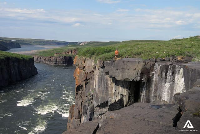 man-standing-on-black-rocks-aabove-the-mountain-river-in-canada