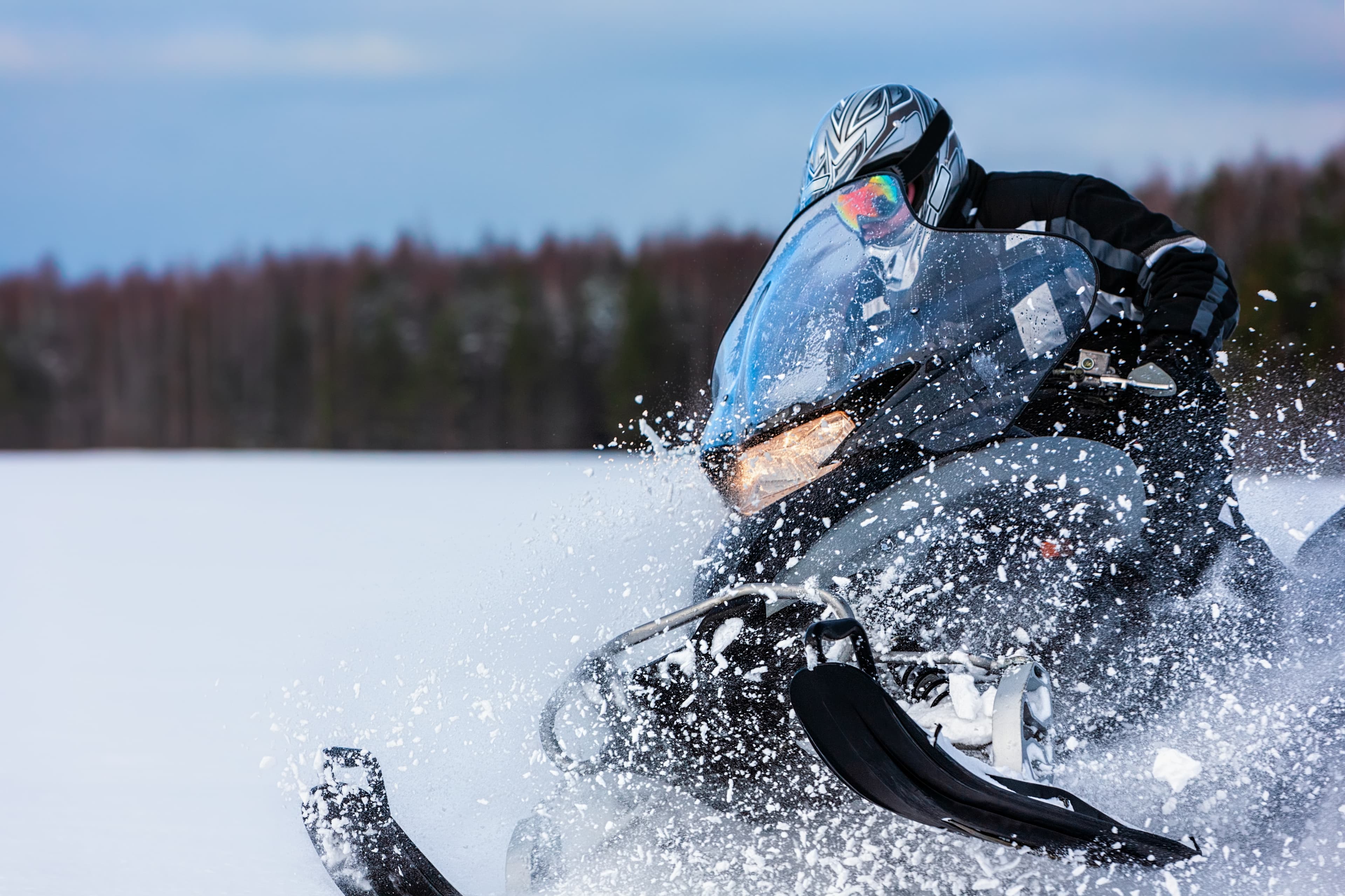 In deep snowdrift snowmobile rider driving fast. Riding with fun in white snow powder during backcountry tour. Extreme sport adventure, outdoor activity during winter holiday on ski mountain resort. In deep powder snowdrift snowmobile rider driving fast.