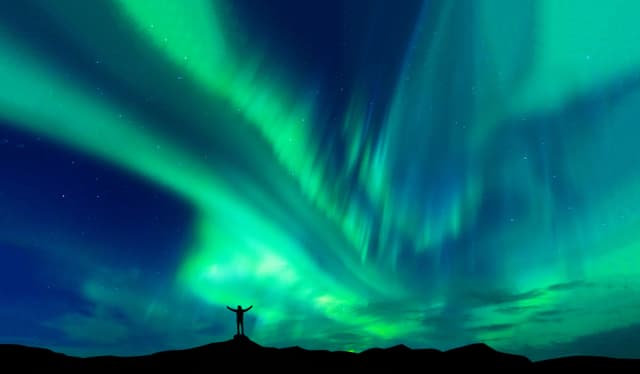 Aurora borealis with silhouette standing man on the mountain.Freedom traveller journey concept Aurora borealis with silhouette standing man on the mountain.Freedom traveller journey concept