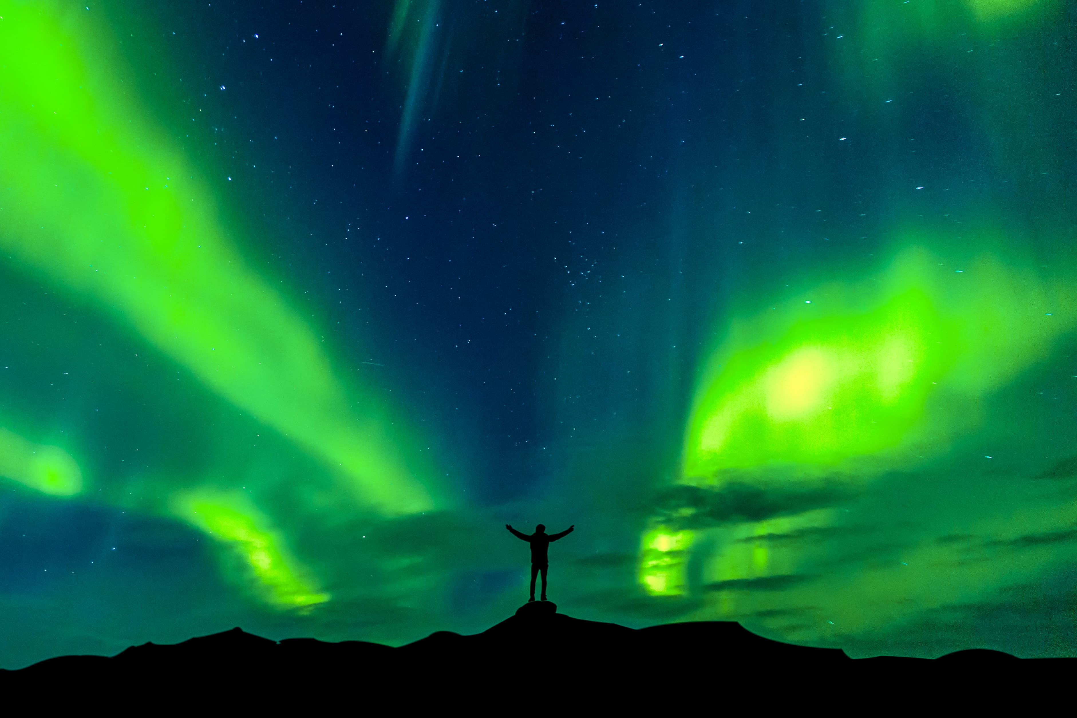 Aurora borealis with silhouette standing man on the mountain.Freedom traveller journey concept Aurora borealis with silhouette standing man on the mountain.Freedom traveller journey concept