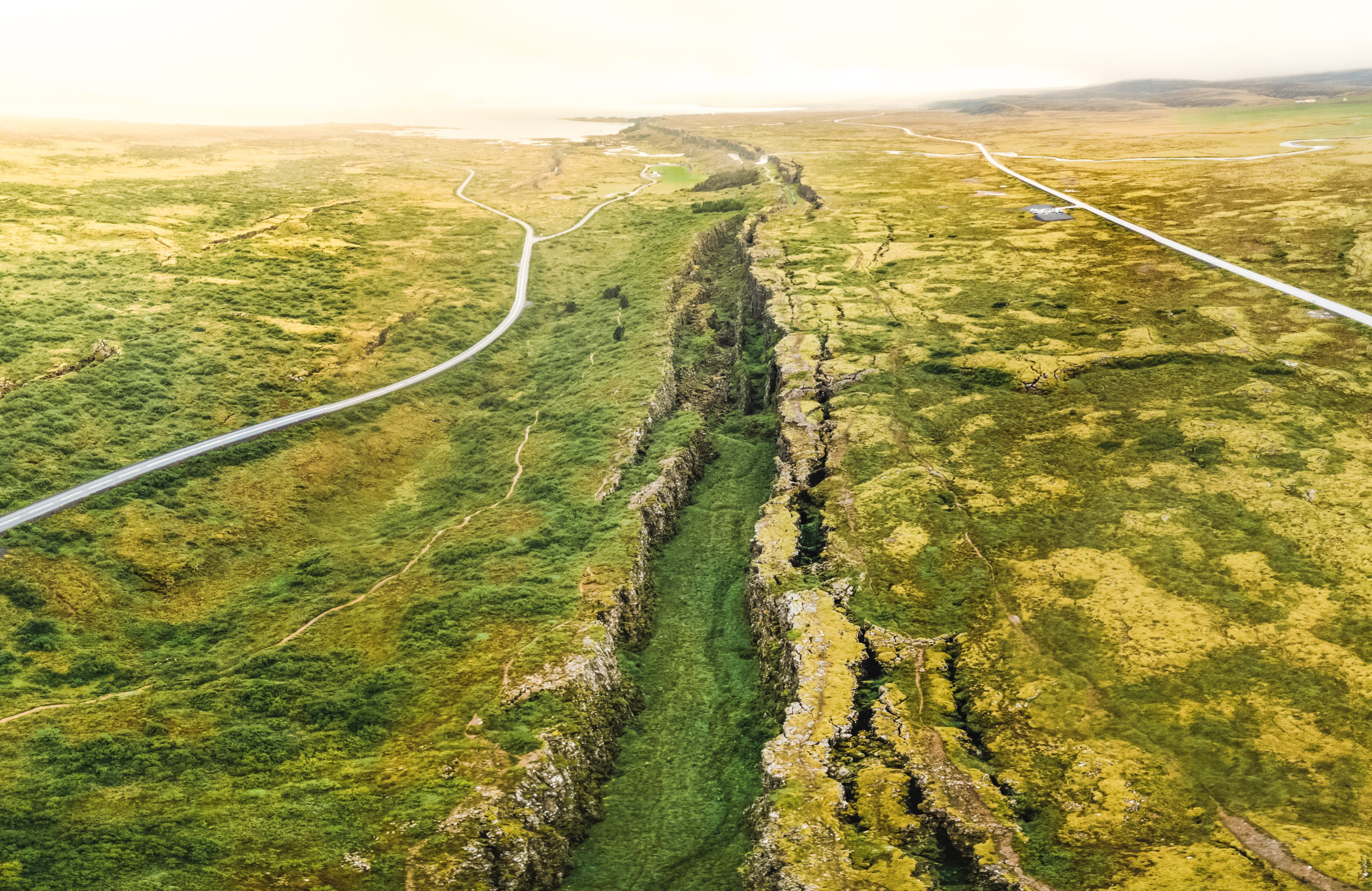 National Park of Thingvellir in Iceland. It is the site of a rift valley that marks the crest of the Mid-Atlantic Ridge. Tectonic plate fault between two roads. National Park of Thingvellir in Iceland. It is the site of a rift valley that marks the crest of the Mid-Atlantic Ridge.