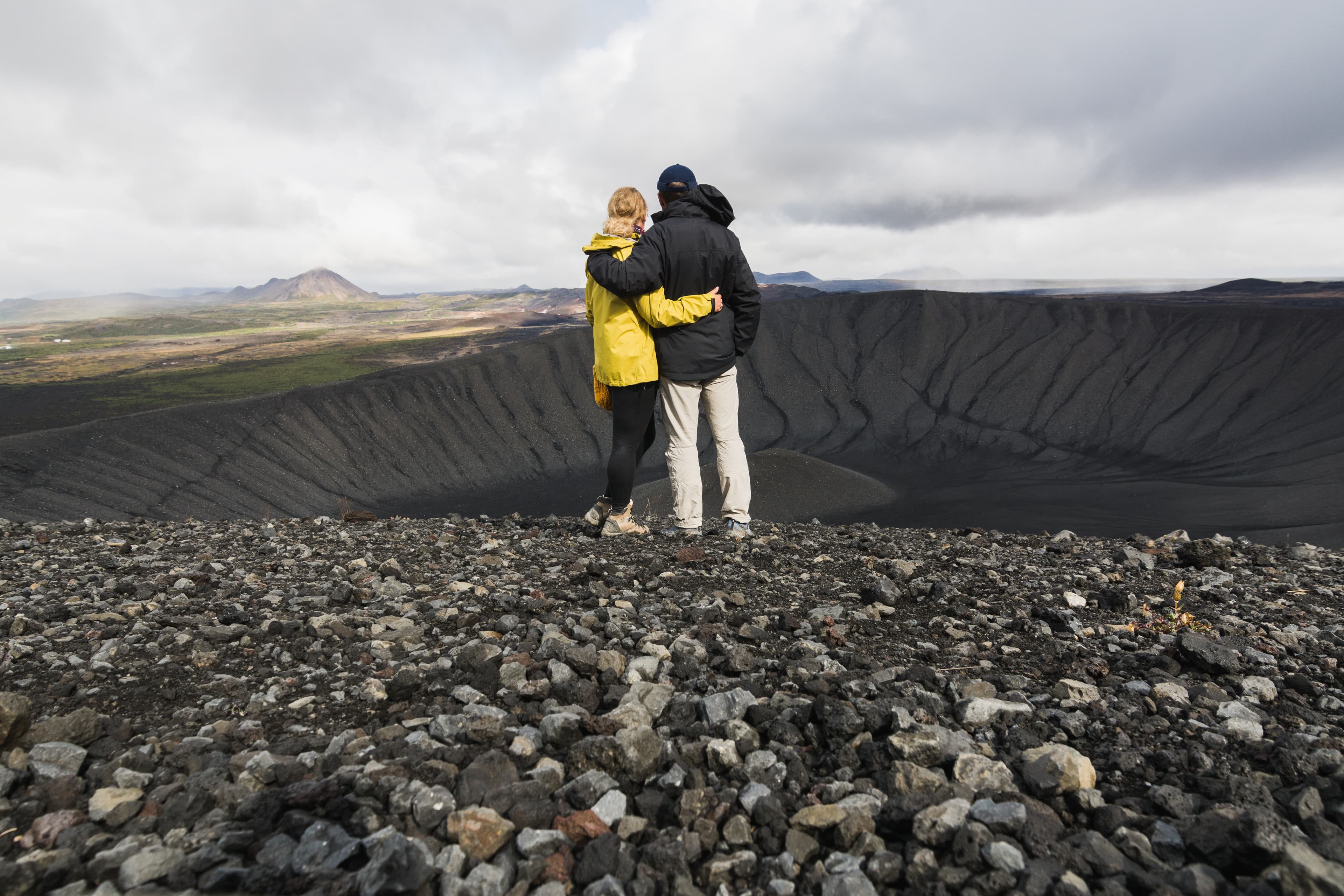 Young couple standing in the crater of Hverfjall volcano in Myvatn area, Iceland. couple-standing -crater-hverfjall-iceland