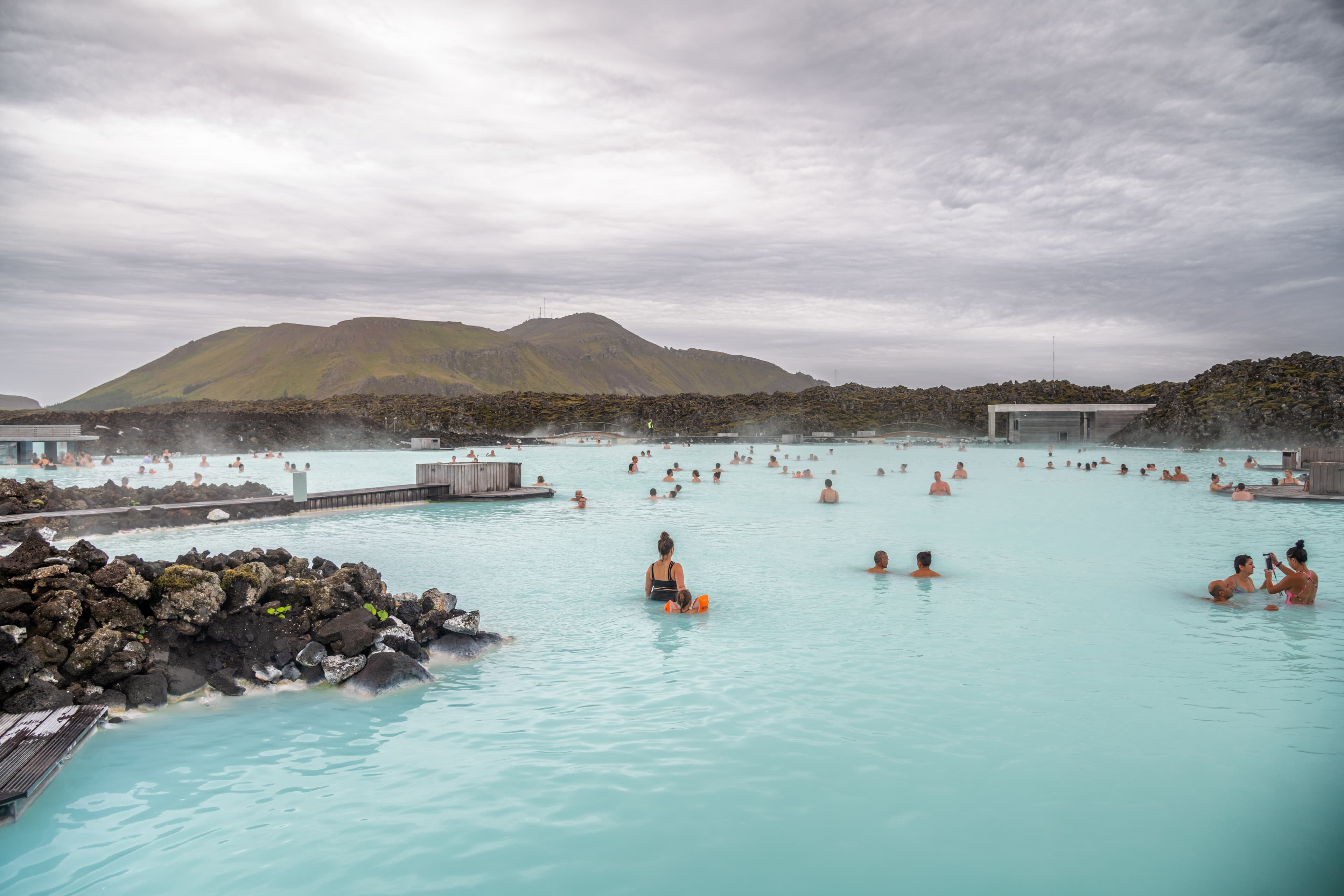 BLUE LAGOON, ICELAND - JULY 31, 2019: Tourists and locals enjoy hot water of natural pools in famous Blue Lagoon. BLUE LAGOON, ICELAND - JULY 31, 2019: Tourists and locals enjoy hot water of natural pools in famous Blue Lagoon