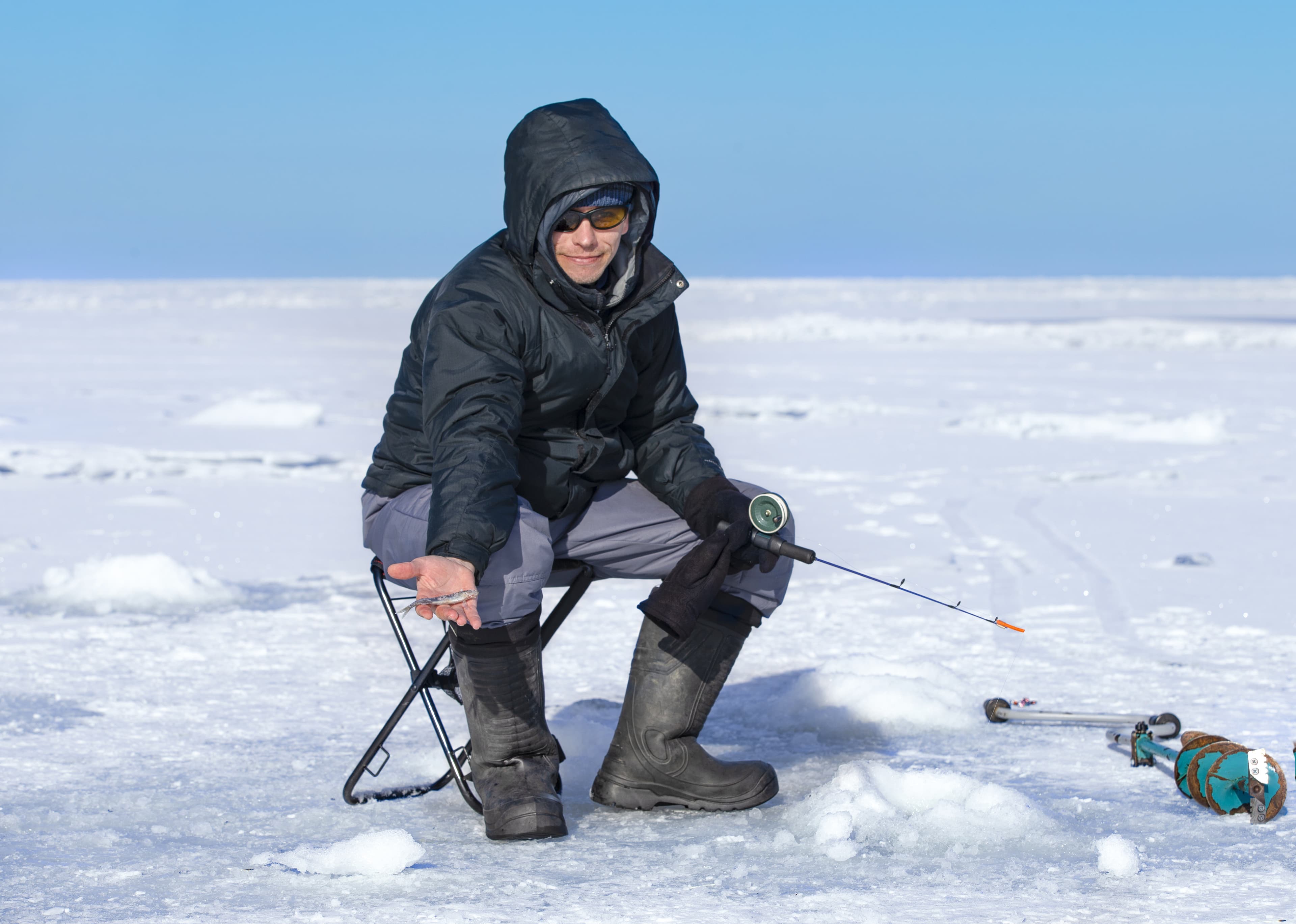 Man ice fishing on a frozen Gulf of Finland Man ice fishing on a frozen Gulf of Finland