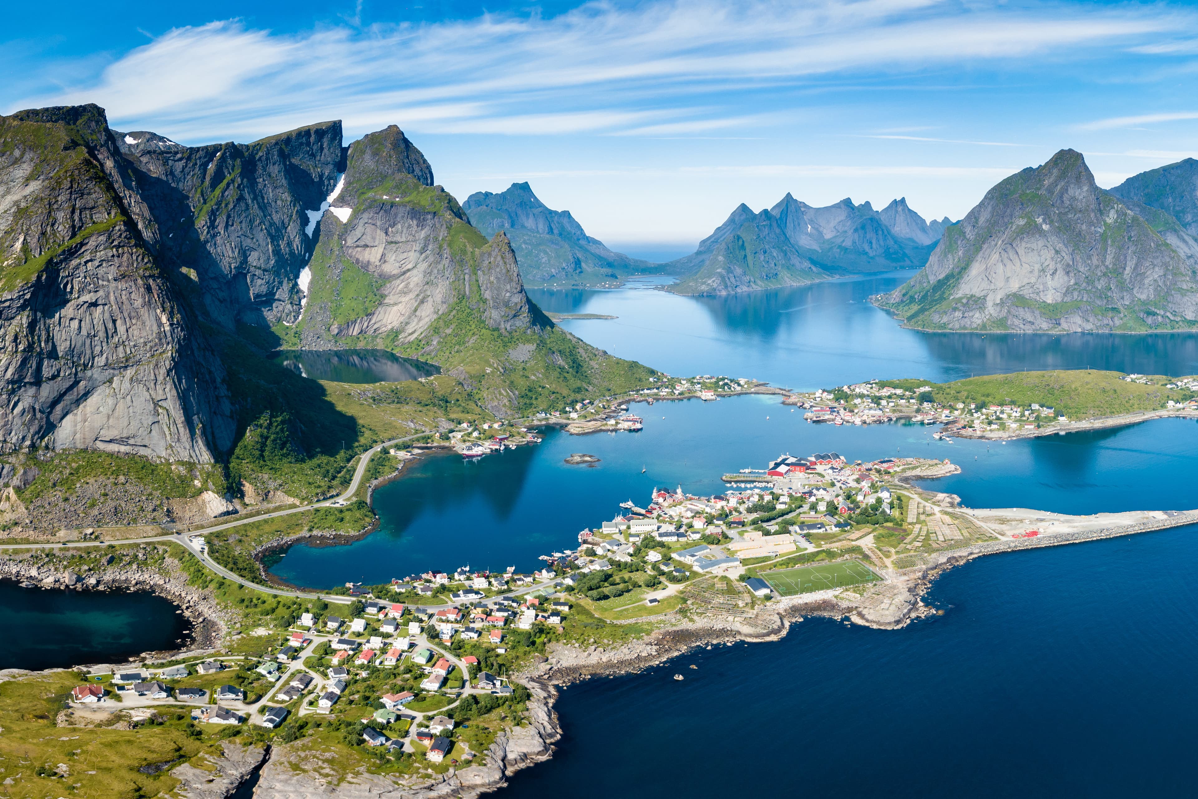 Reine Lofoten Norway, aerial view of Norwegian traditional fishing village above polar circle with blue sea and mountains during sunny arctic summer, famous for Reinebringen hike Reine Lofoten Norway, aerial view of Norwegian traditional fishing village above polar circle with blue sea and mountains during sunny arctic summer, famous for Reinebringen hike