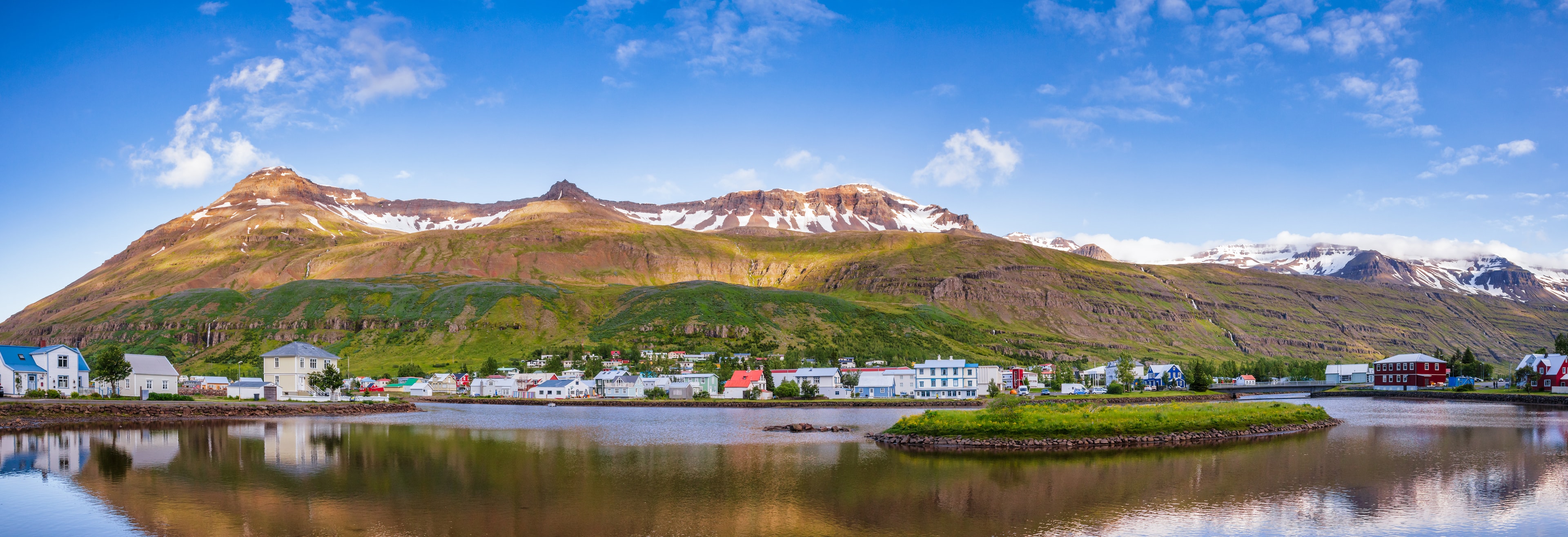 Panoramic view of Seydisfjordur with houses and surrounding landscape reflecting in Fjardara lake. Seydisfjordur is a small picturesque town and port at the innermost point of Seydisfjordur fjord in Eastern Iceland, Scandinavia Seydisfjordur panorama Eastern Iceland Scandinavia