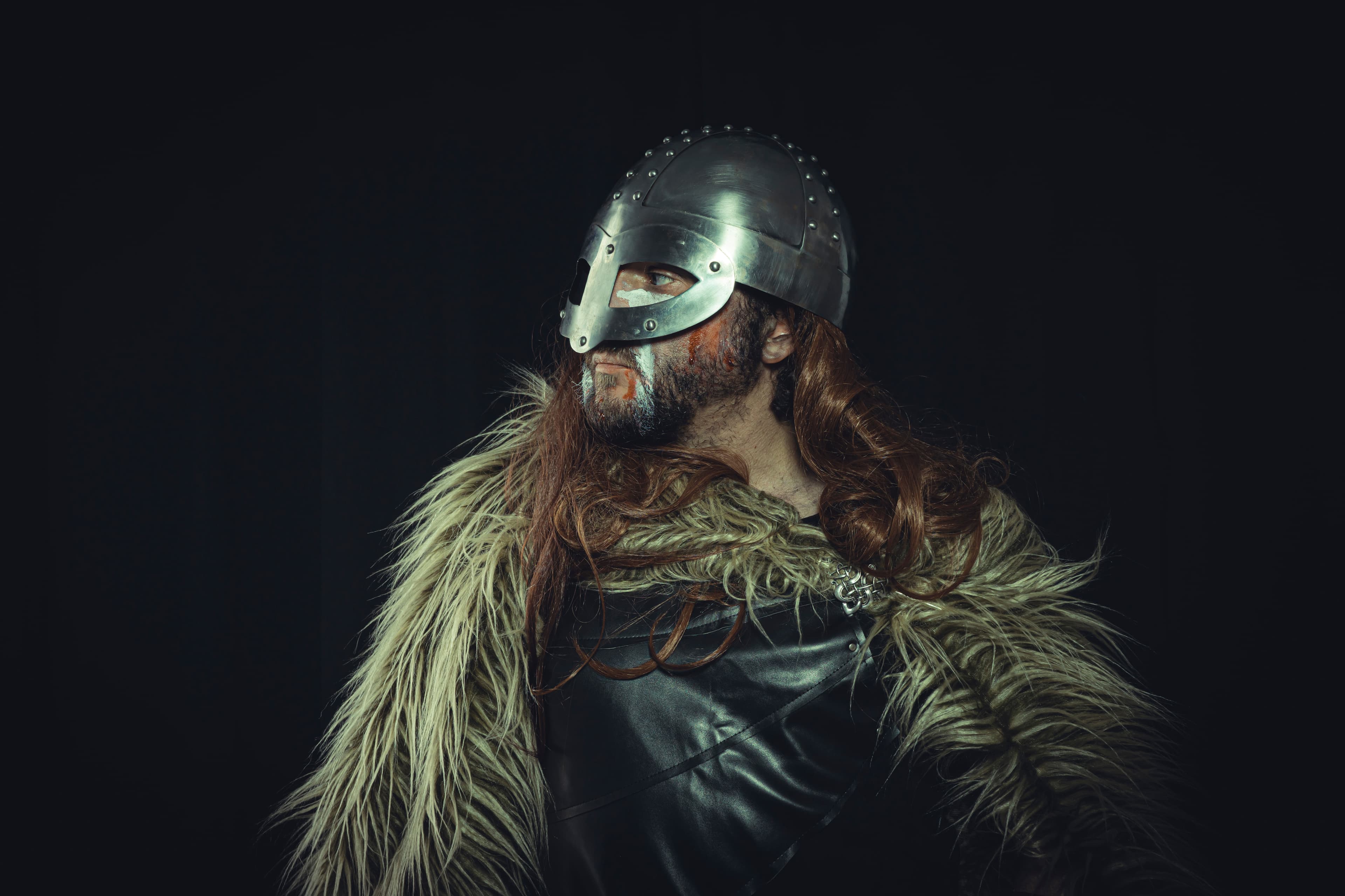 Viking, Scandinavian warrior with helmet and war paintings, wears a sword and a cape of animal skin Viking, Scandinavian warrior with helmet and war paintings, wears a sword and a cape of animal skin