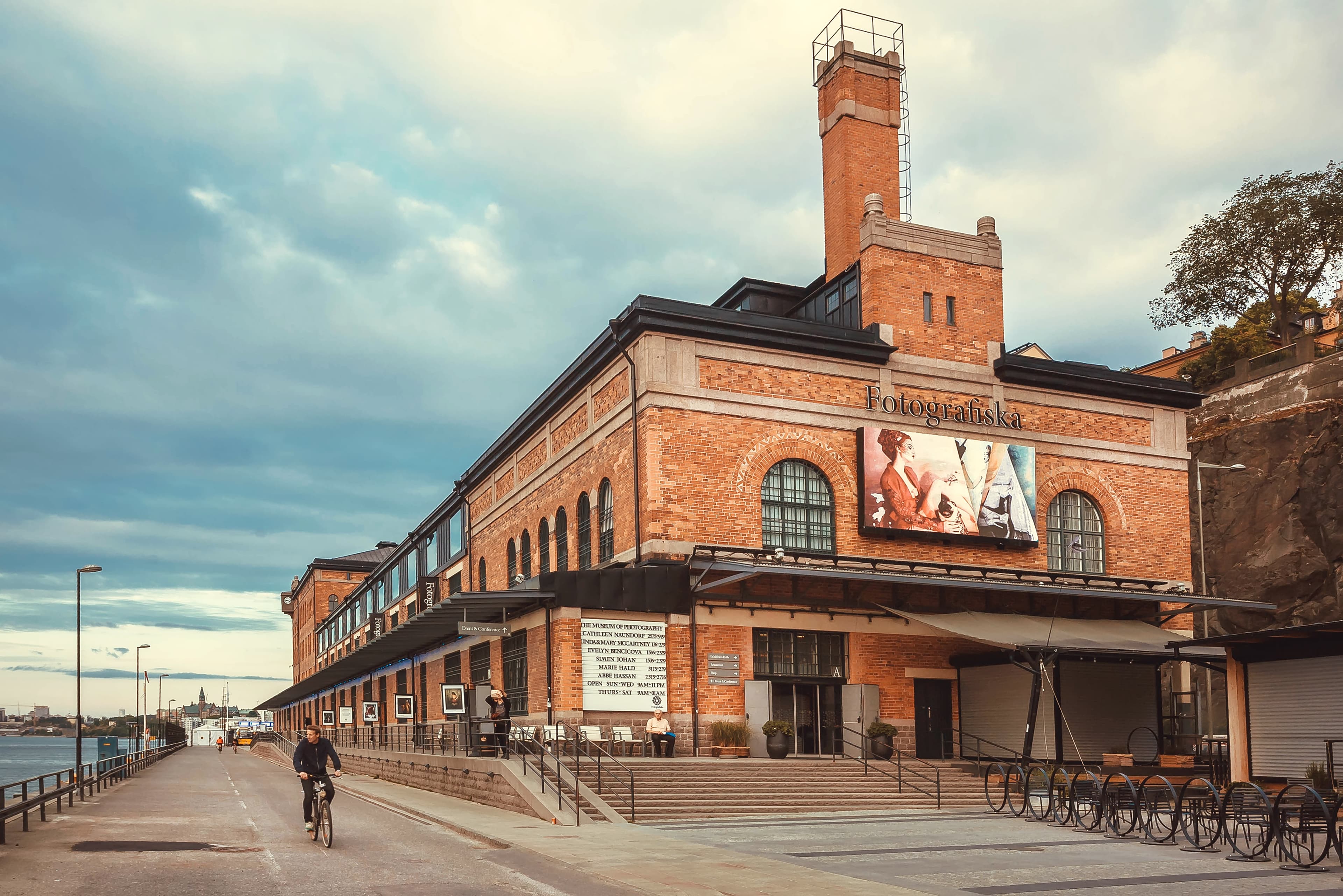 STOCKHOLM, SWEDEN - JUN 16, 2018: Cyclist driving past bilding of the cultural center Fotografiska with brick walls on June 16, 2018. Sweden with 10,5 million peope ranks high in life expectancy STOCKHOLM, SWEDEN - JUN 16, 2018: Cyclist driving past bilding of the cultural center Fotografiska with brick walls on June 16, 2018. Sweden with 10,5 million peope ranks high in life expectancy
