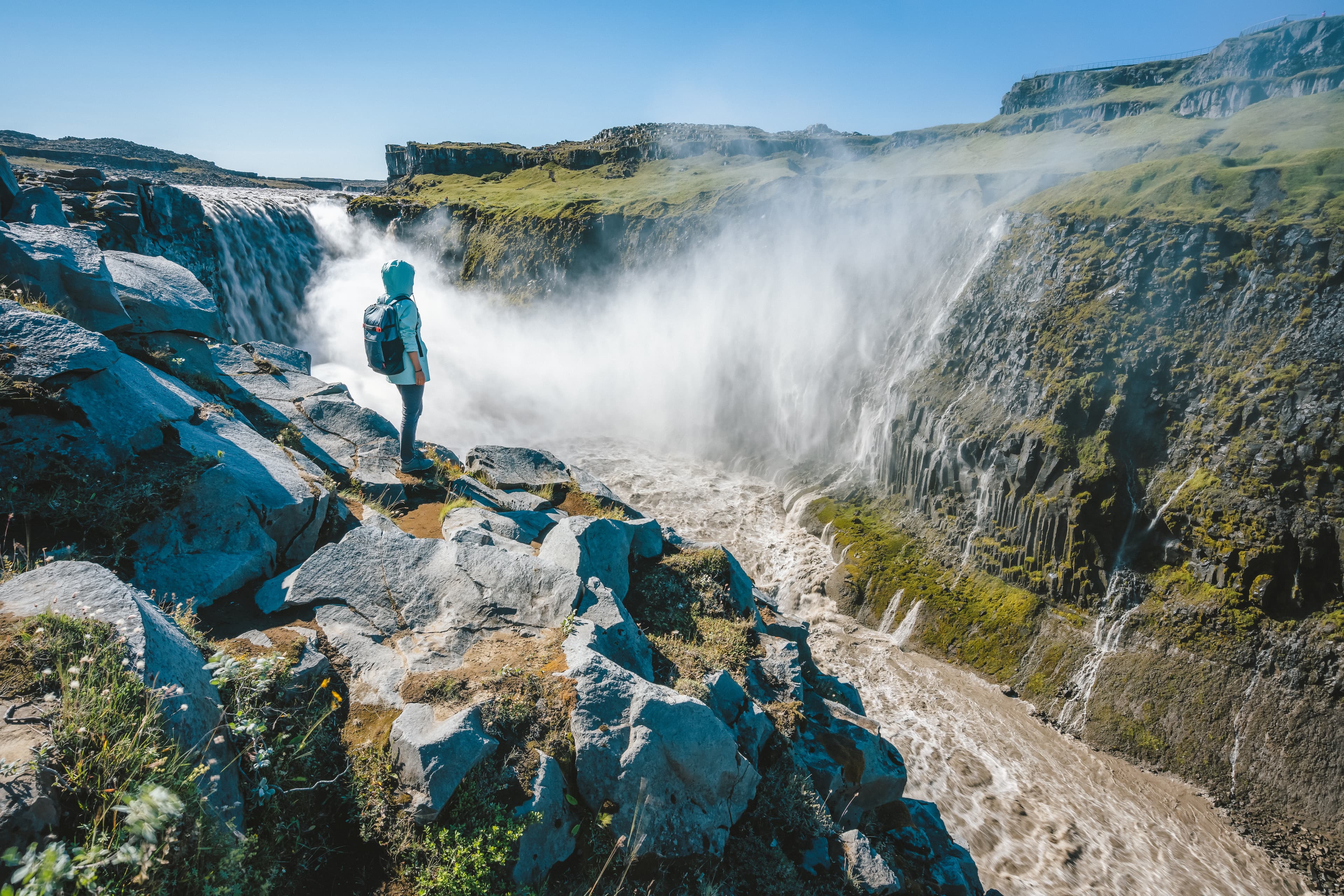 Woman on the cliff of Dettifoss most powerful waterfall in Europe, Iceland Woman on the cliff of Dettifoss most powerful waterfall in Europe, Iceland