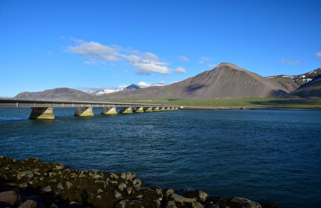 The girder bridge leading to Borgarnes in Iceland, crossing the ocean. Mountains in the background. The bridge over the ocean leading to Borgarnes, a town in Iceland.