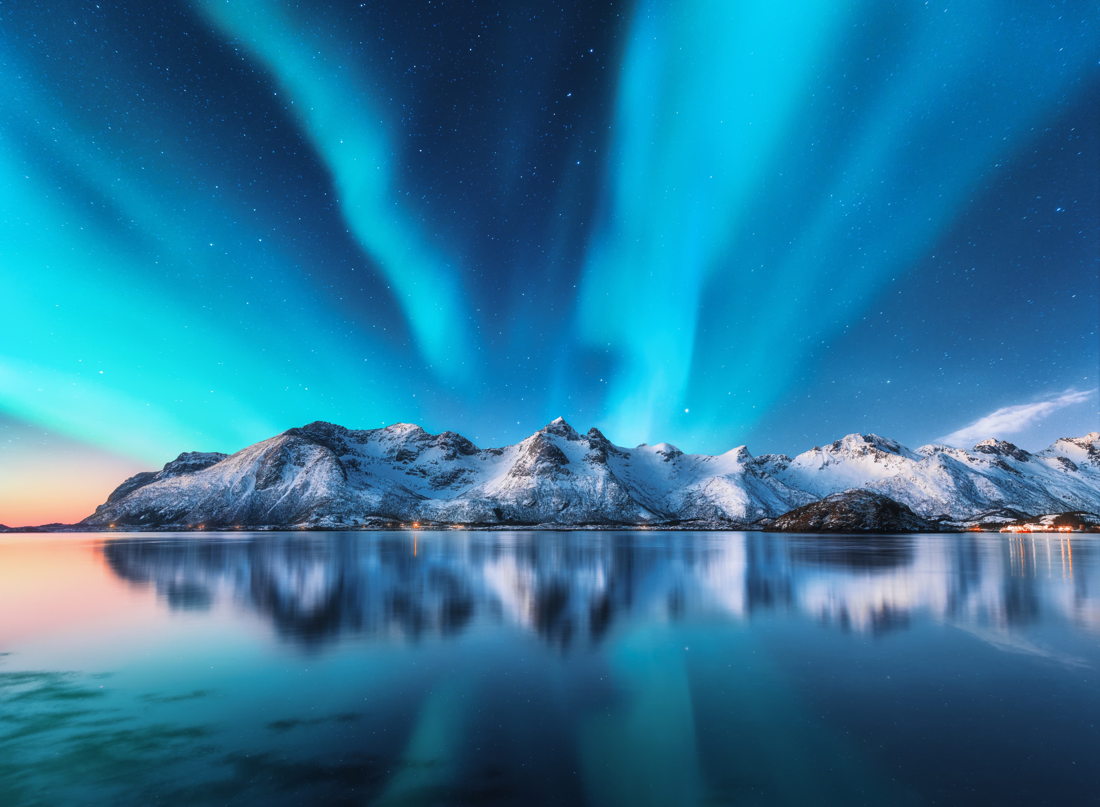 Northern lights and snow covered mountains in Lofoten islands, Norway. Aurora borealis. Starry sky with polar lights and snowy rocks reflected in water. Night winter landscape with aurora, sea. Nature Northern lights and snow covered mountains in Lofoten islands, Norway. Aurora borealis. Starry sky with polar lights and snowy rocks reflected in water. Night winter landscape with aurora, sea. Nature