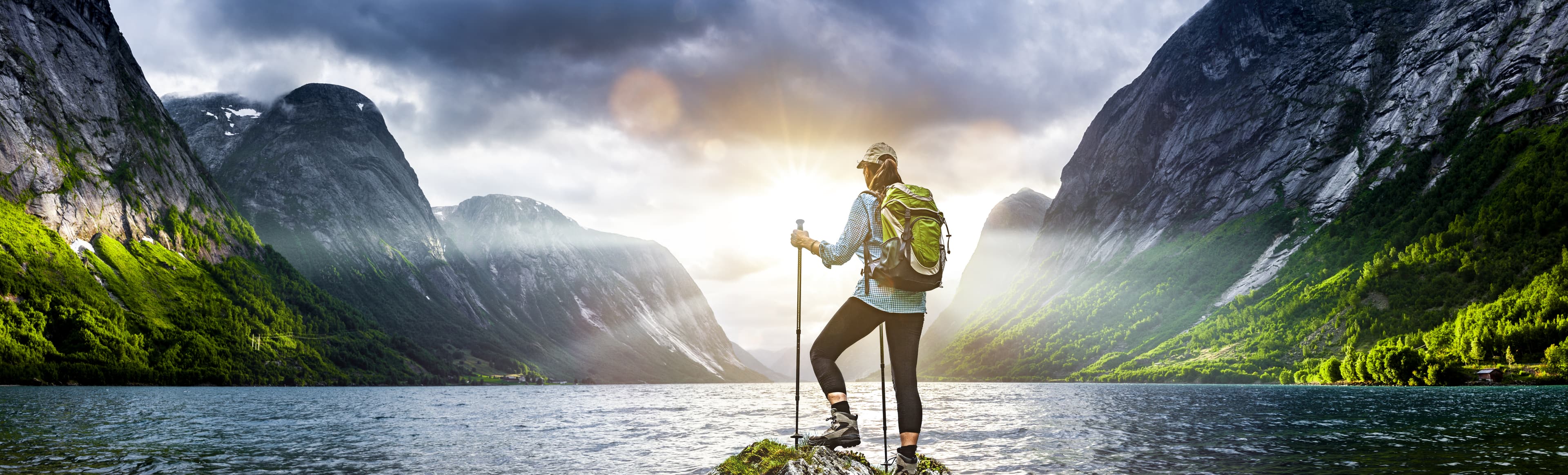 Frau mit Rucksack beim Wandern an einem Fjord in Norwegen Frau mit Rucksack beim Wandern an einem Fjord in Norwegen