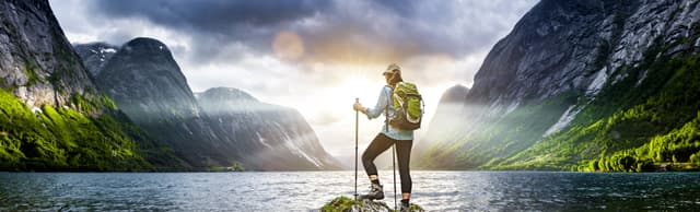Frau mit Rucksack beim Wandern an einem Fjord in Norwegen Frau mit Rucksack beim Wandern an einem Fjord in Norwegen