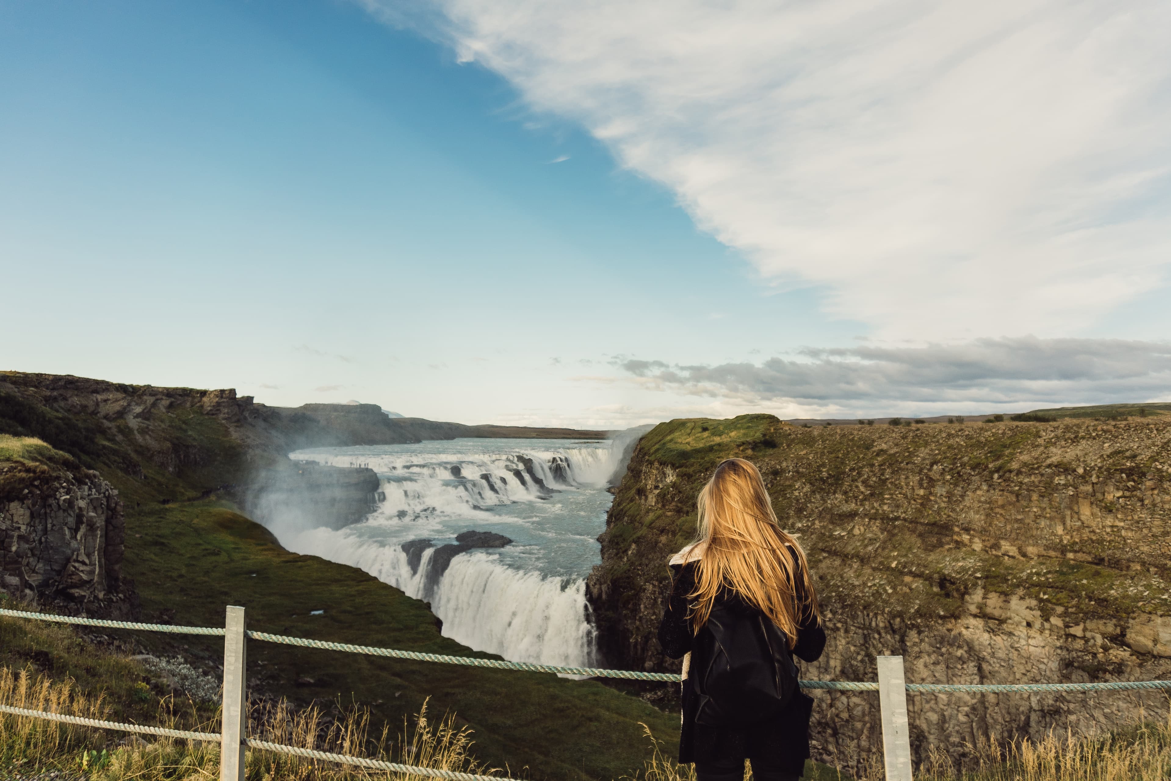 back view of young woman looking at scenic majestic waterfall in Iceland young-woman-gullfoss-waterfall-celand