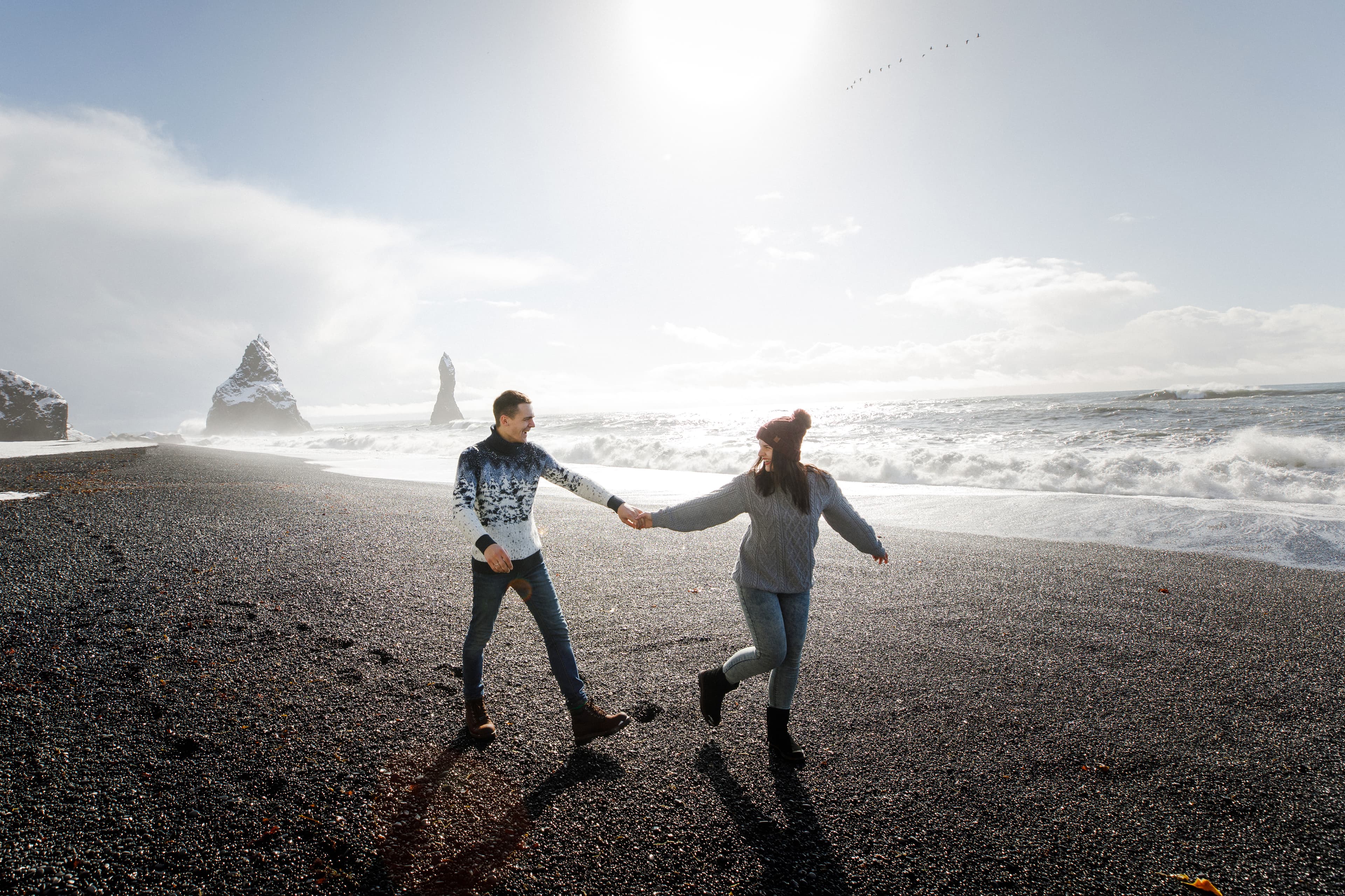young beautiful couple walking on a black beach near the atlantic ocean in Iceland