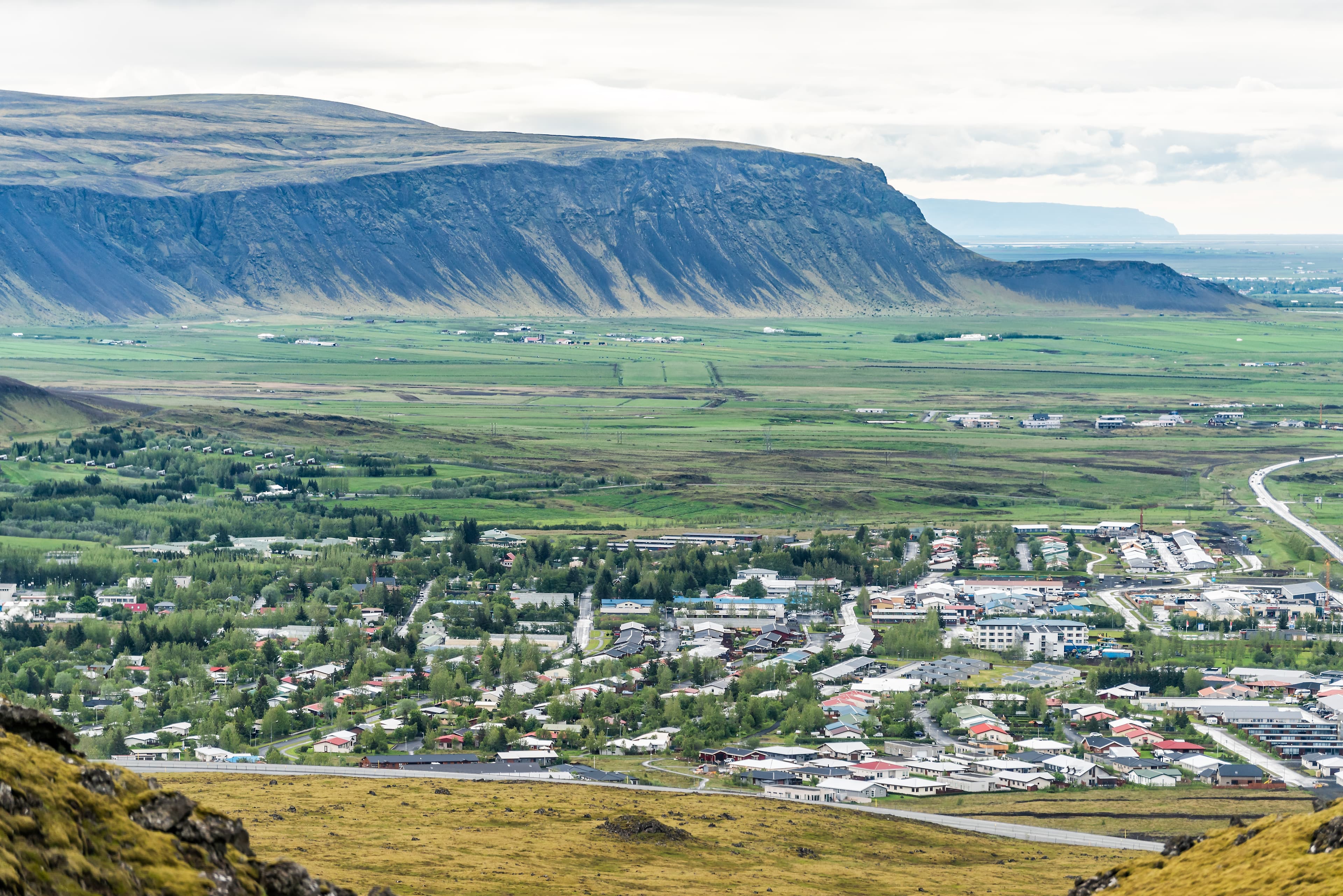 Aerial view down of Hveragerdi, Iceland town, city or village with houses, cityscape or skyline landscape, mountain cliff, in valley Aerial view down of Hveragerdi, Iceland town, city or village with houses, cityscape or skyline landscape, mountain cliff, in valley