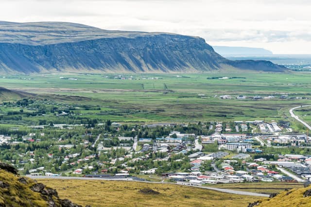 Aerial view down of Hveragerdi, Iceland town, city or village with houses, cityscape or skyline landscape, mountain cliff, in valley Aerial view down of Hveragerdi, Iceland town, city or village with houses, cityscape or skyline landscape, mountain cliff, in valley