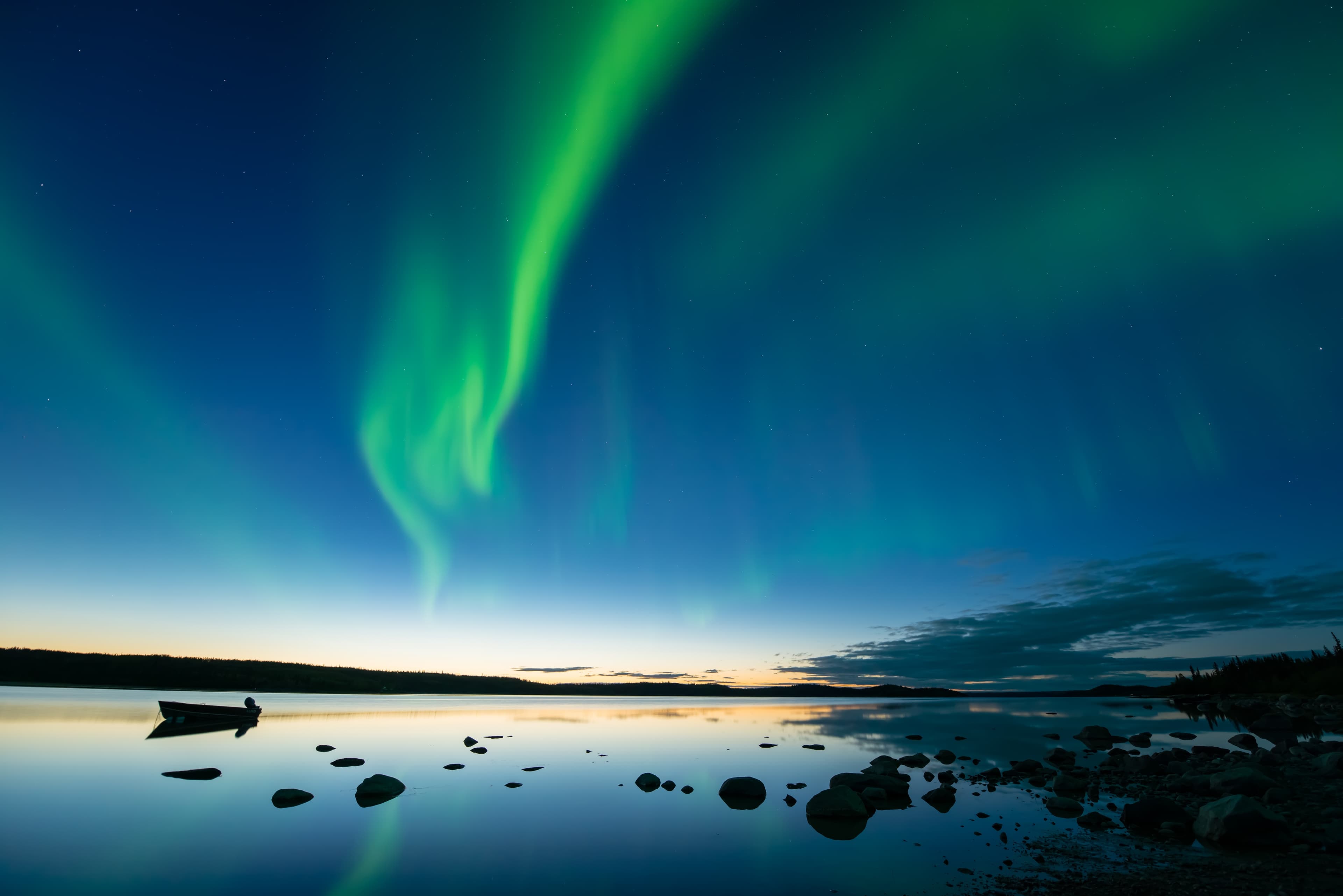 Aurora at Dusk - Bands of curvy aurora borealis appear over a northern rocky lake right after sunset.